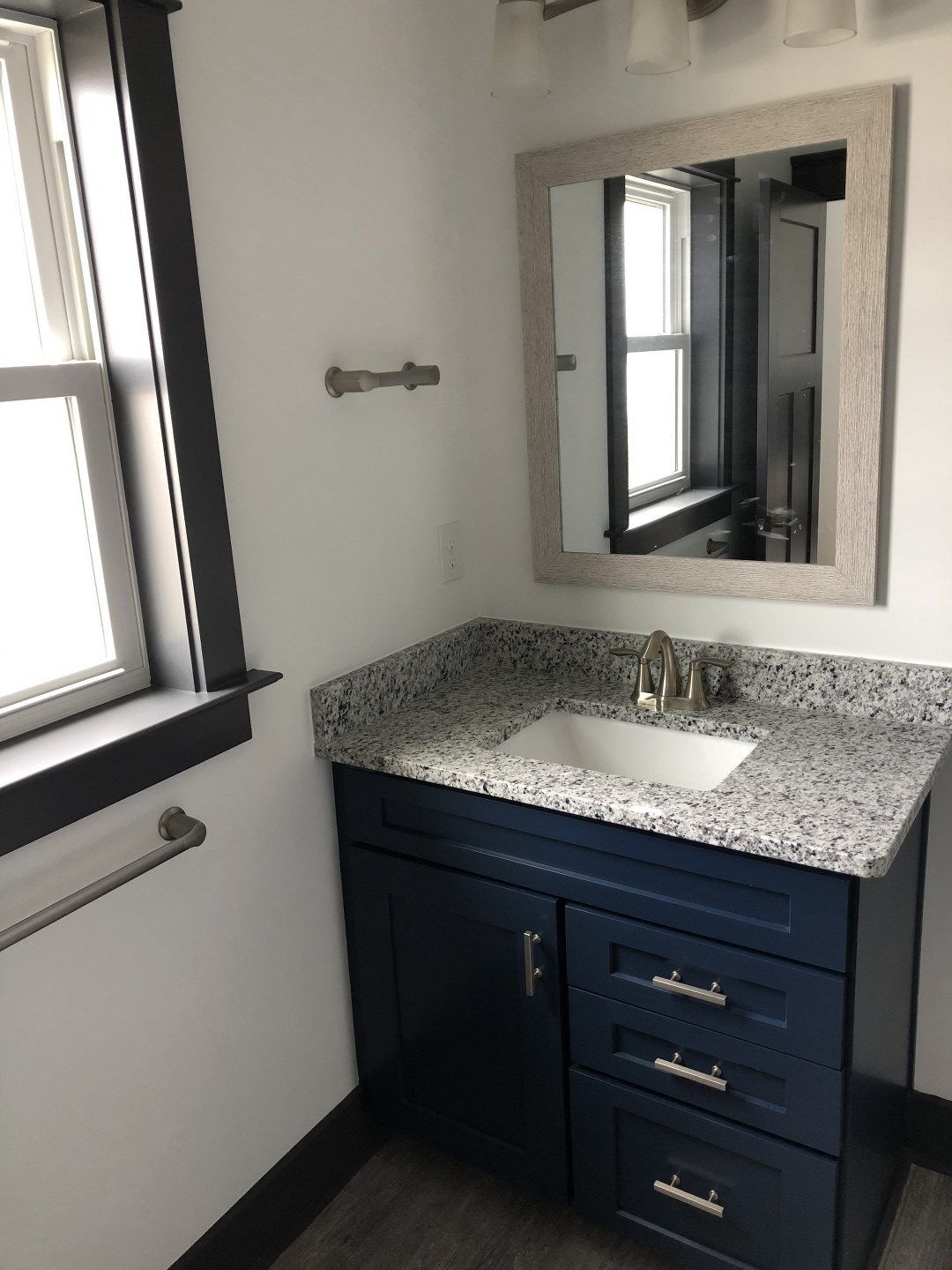 A bathroom with a sink , mirror and window.