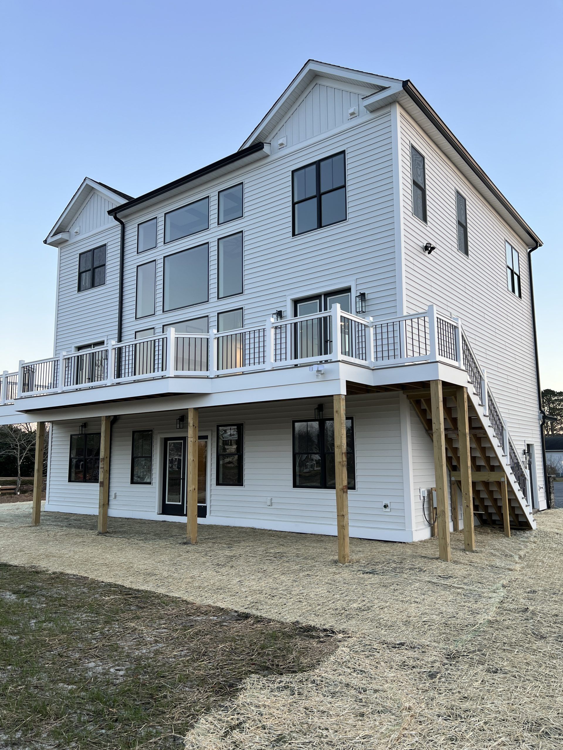 A large white house with a large deck and stairs.