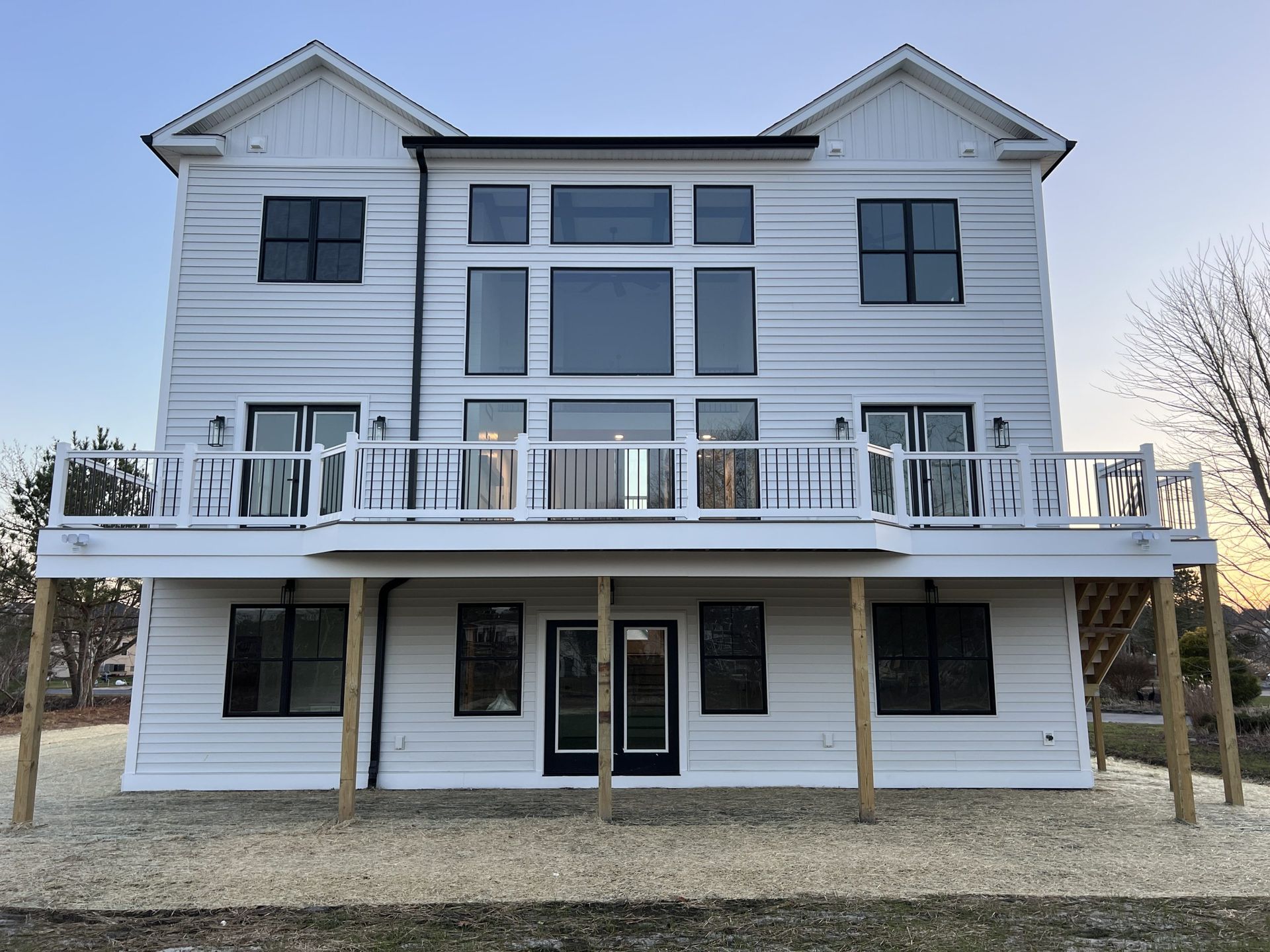 The back of a large white house with a large deck.