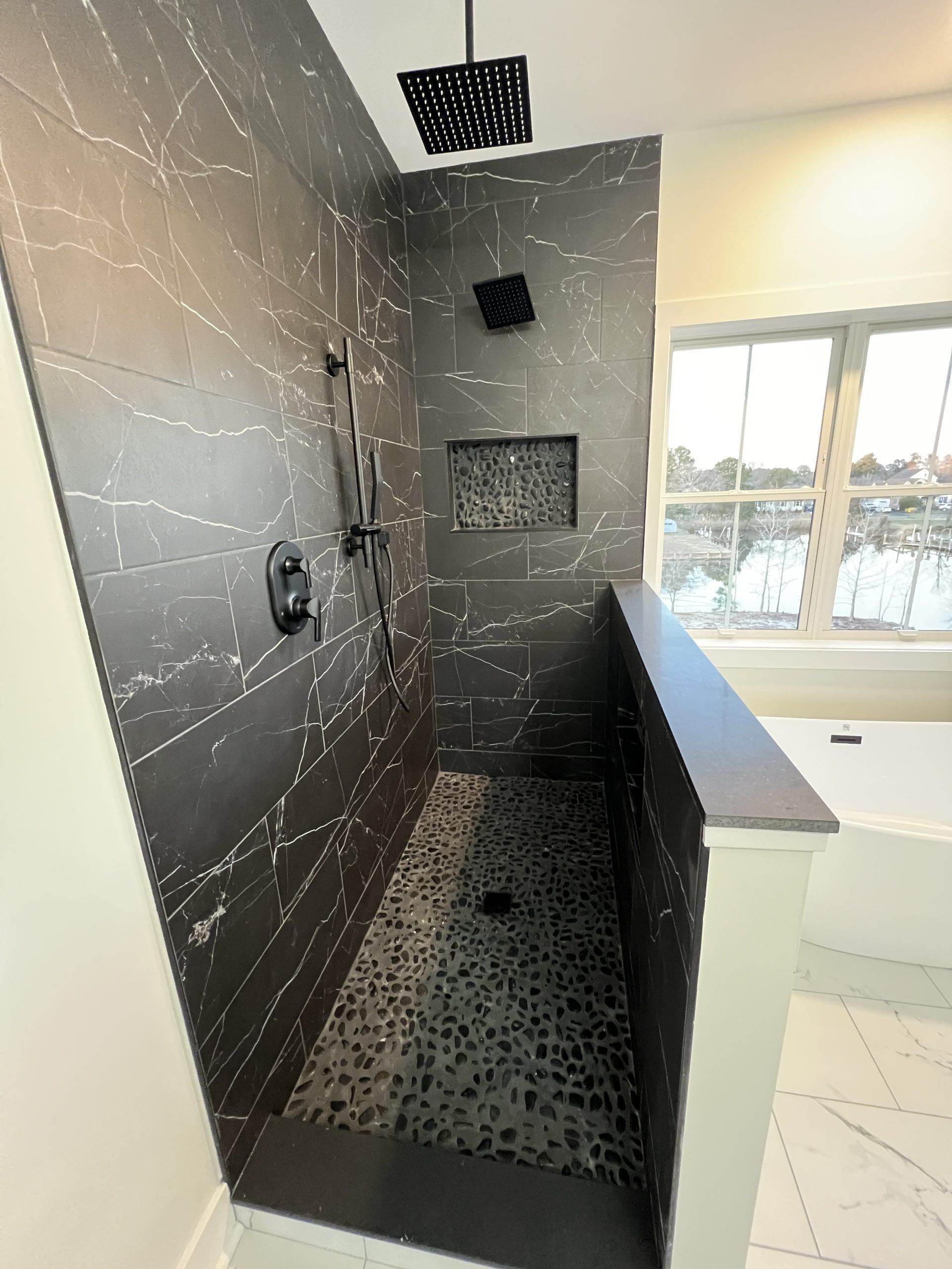 A bathroom with a walk in shower and a window.