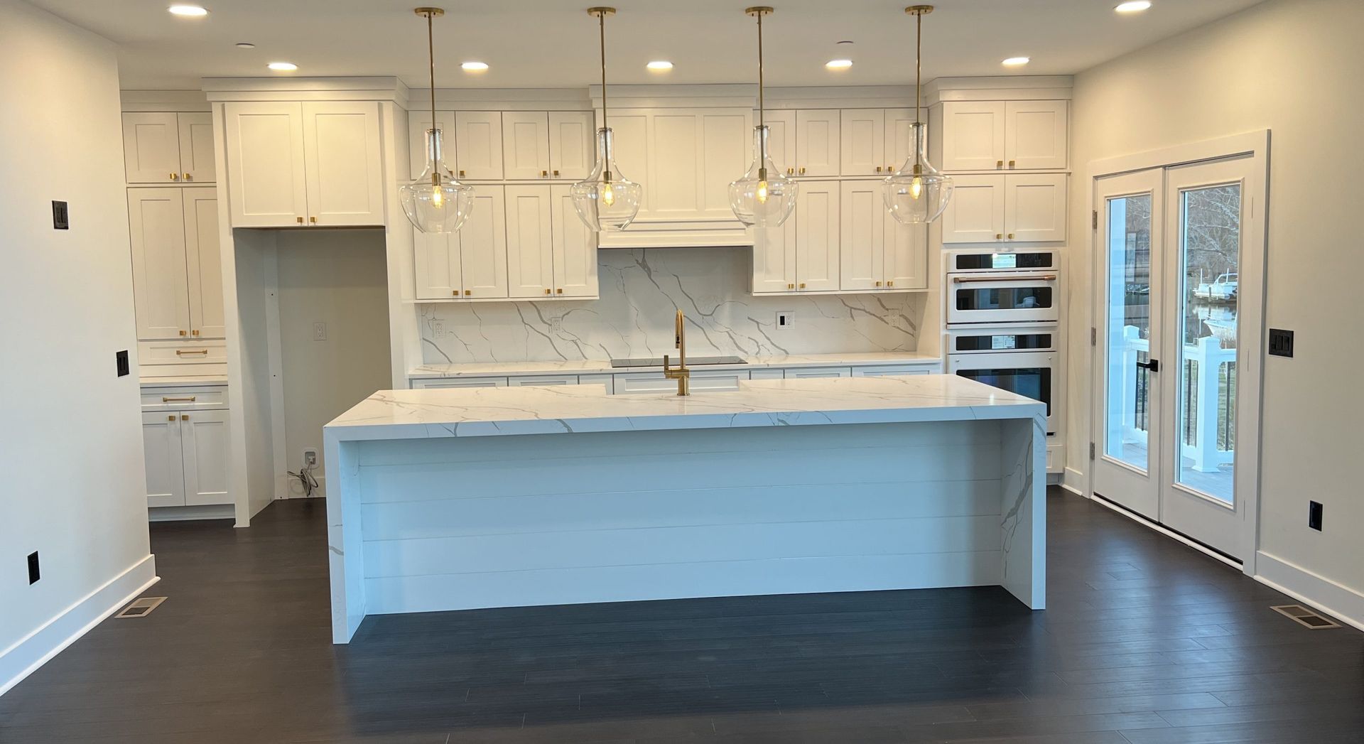 An empty kitchen with white cabinets and a large island.