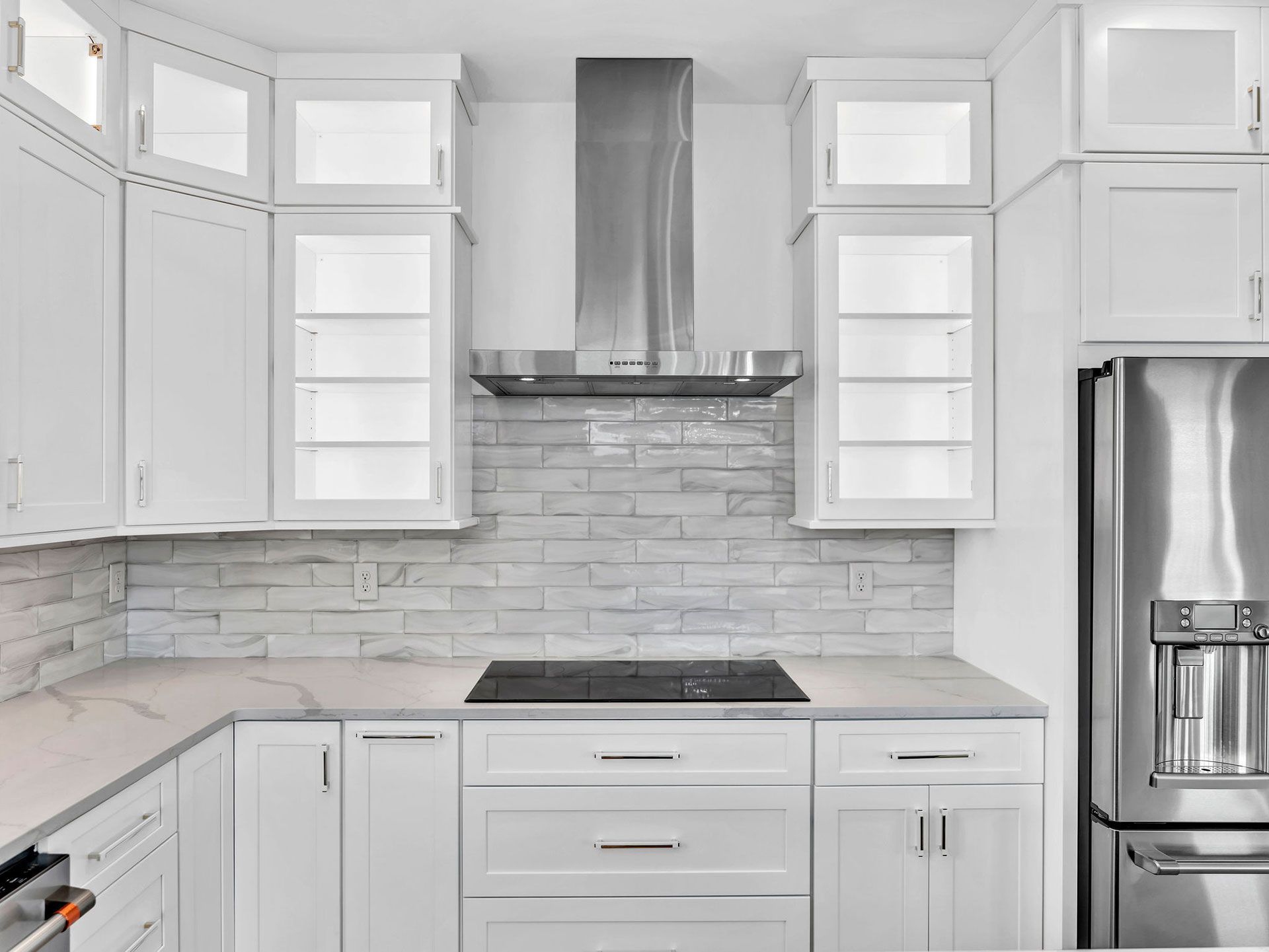 White kitchen with stainless steel appliances, cabinets, and a range hood.