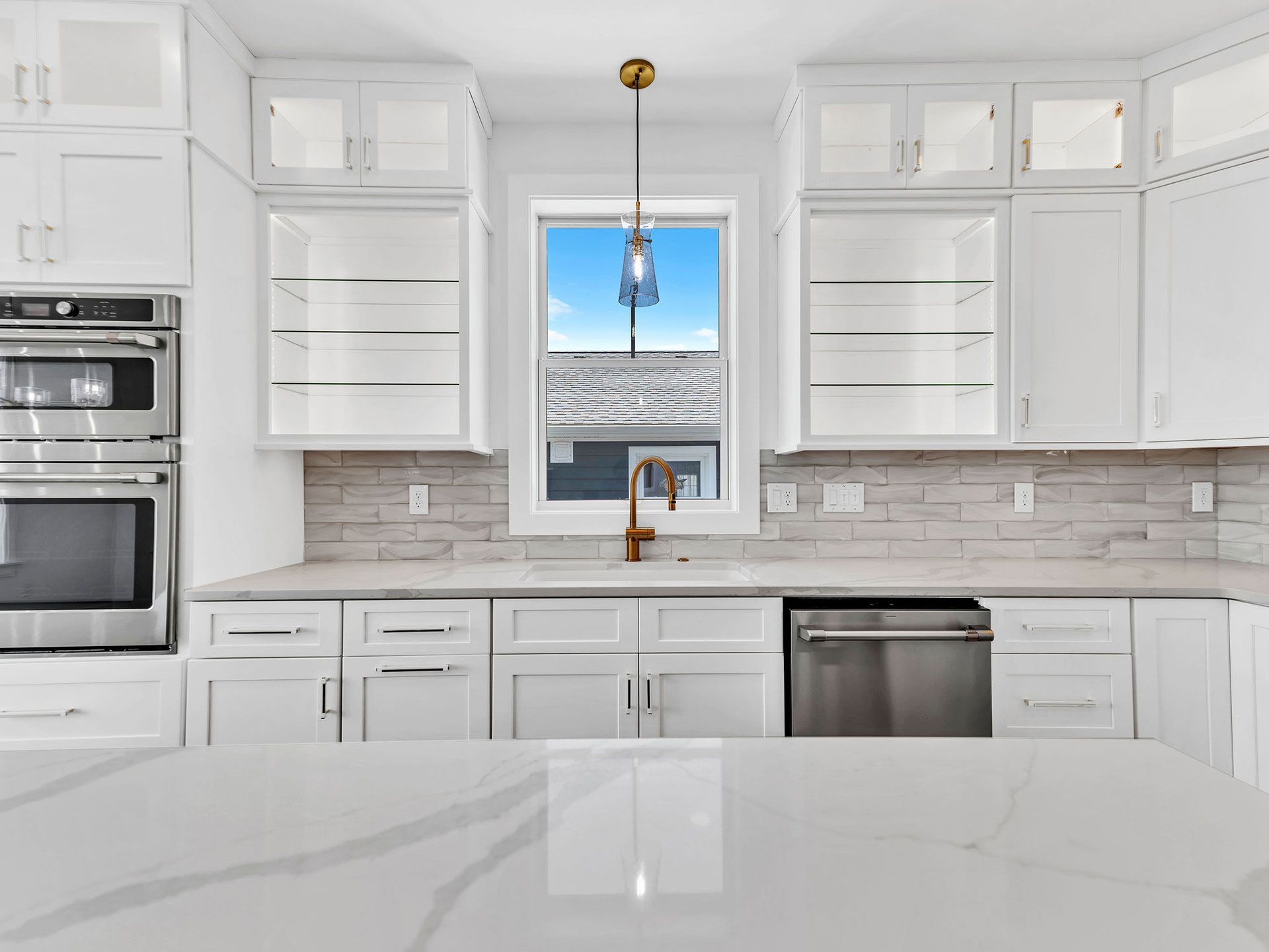 White kitchen with cabinets, window, and a marble countertop island.
