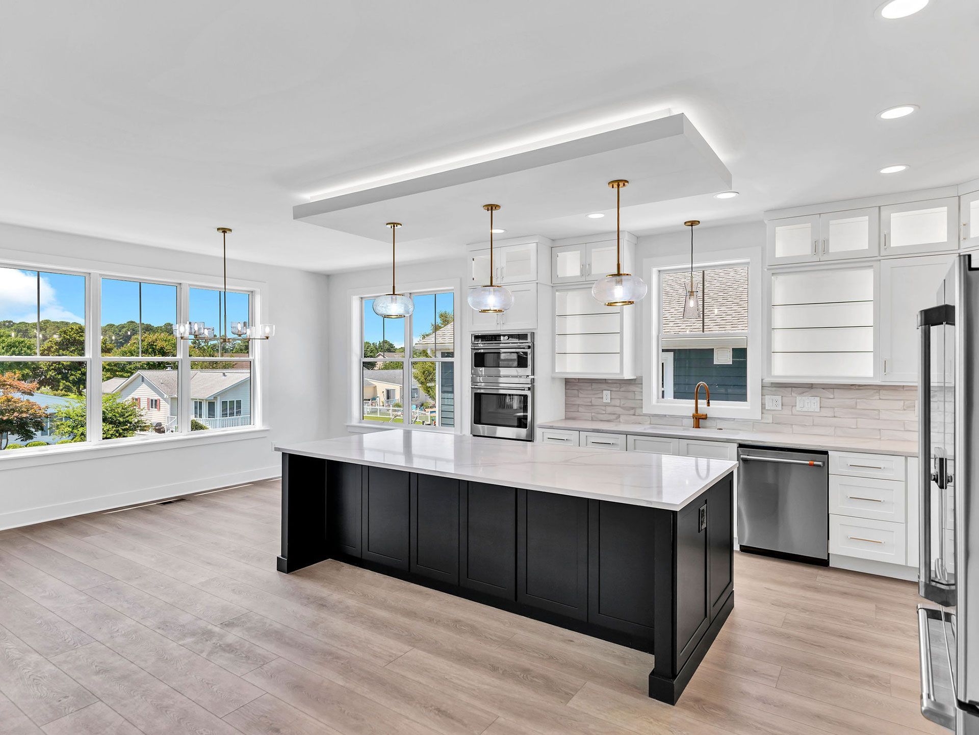 Modern kitchen with a black island, white cabinets, and large windows.