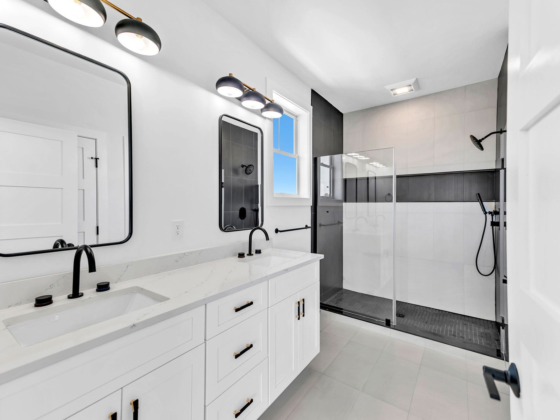 Modern bathroom with white vanity, black fixtures, and walk-in shower with dark gray tile.