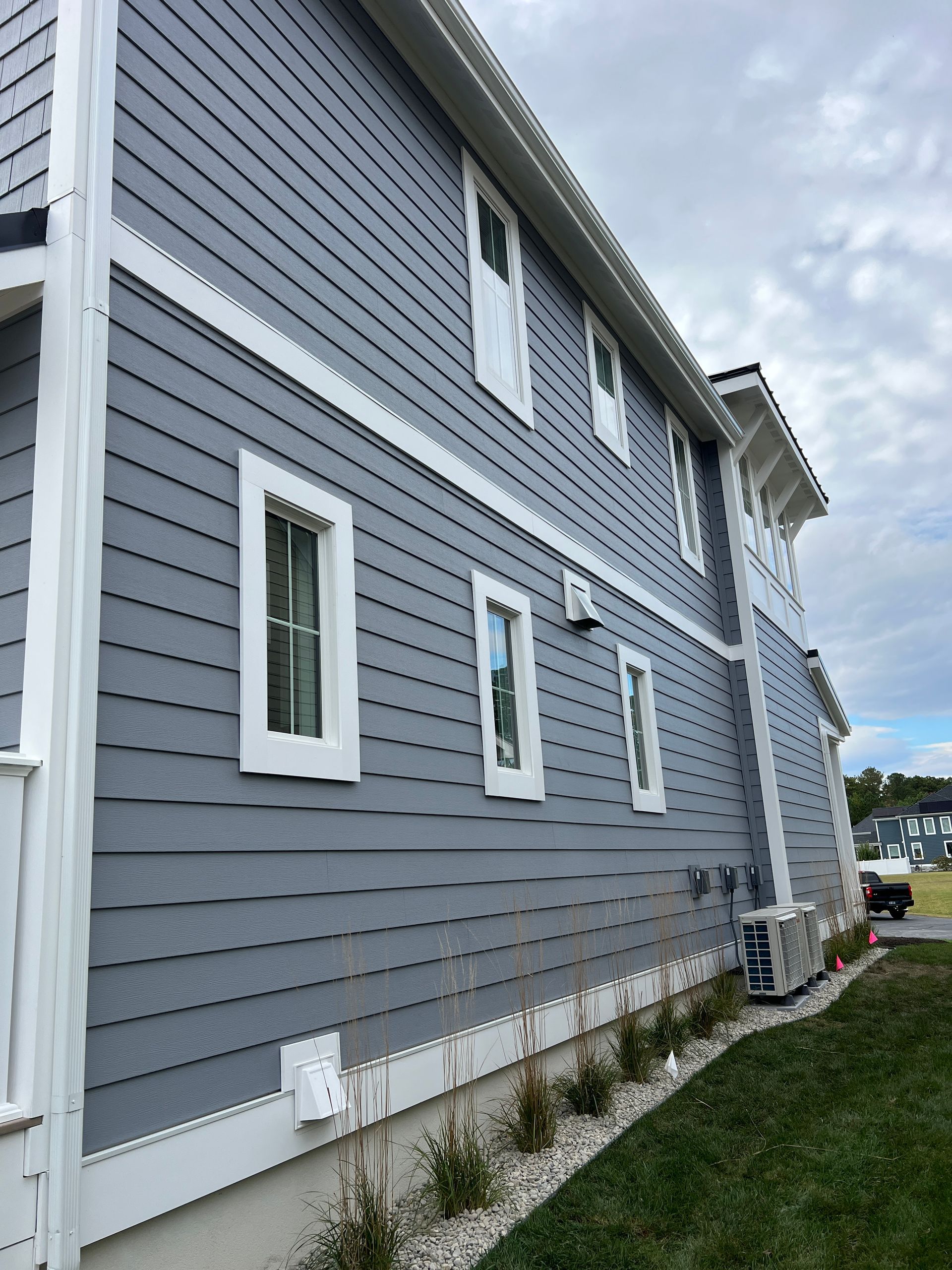 A large gray house with white trim and windows on a cloudy day.