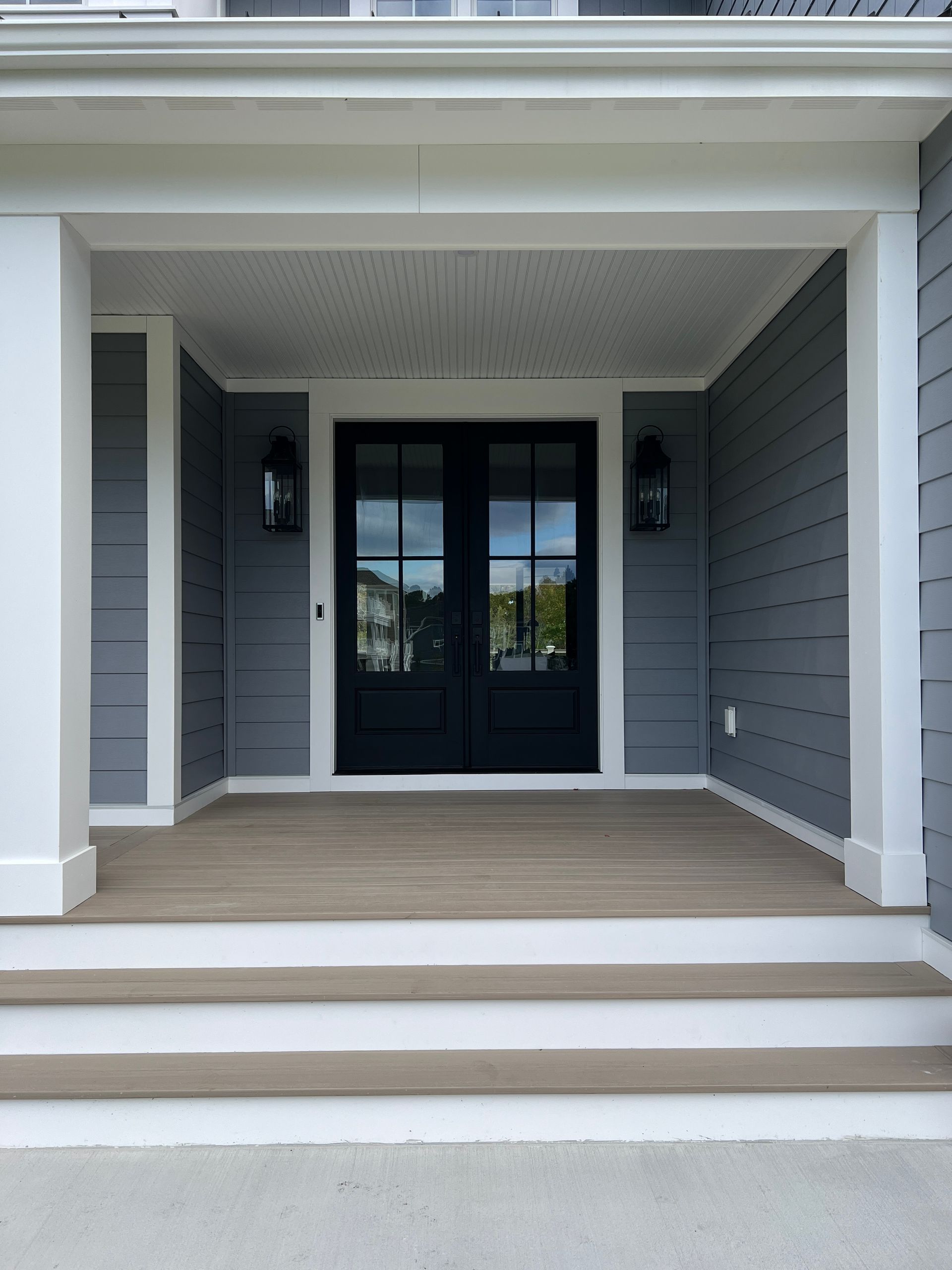 The front door of a house with a black door and a porch.