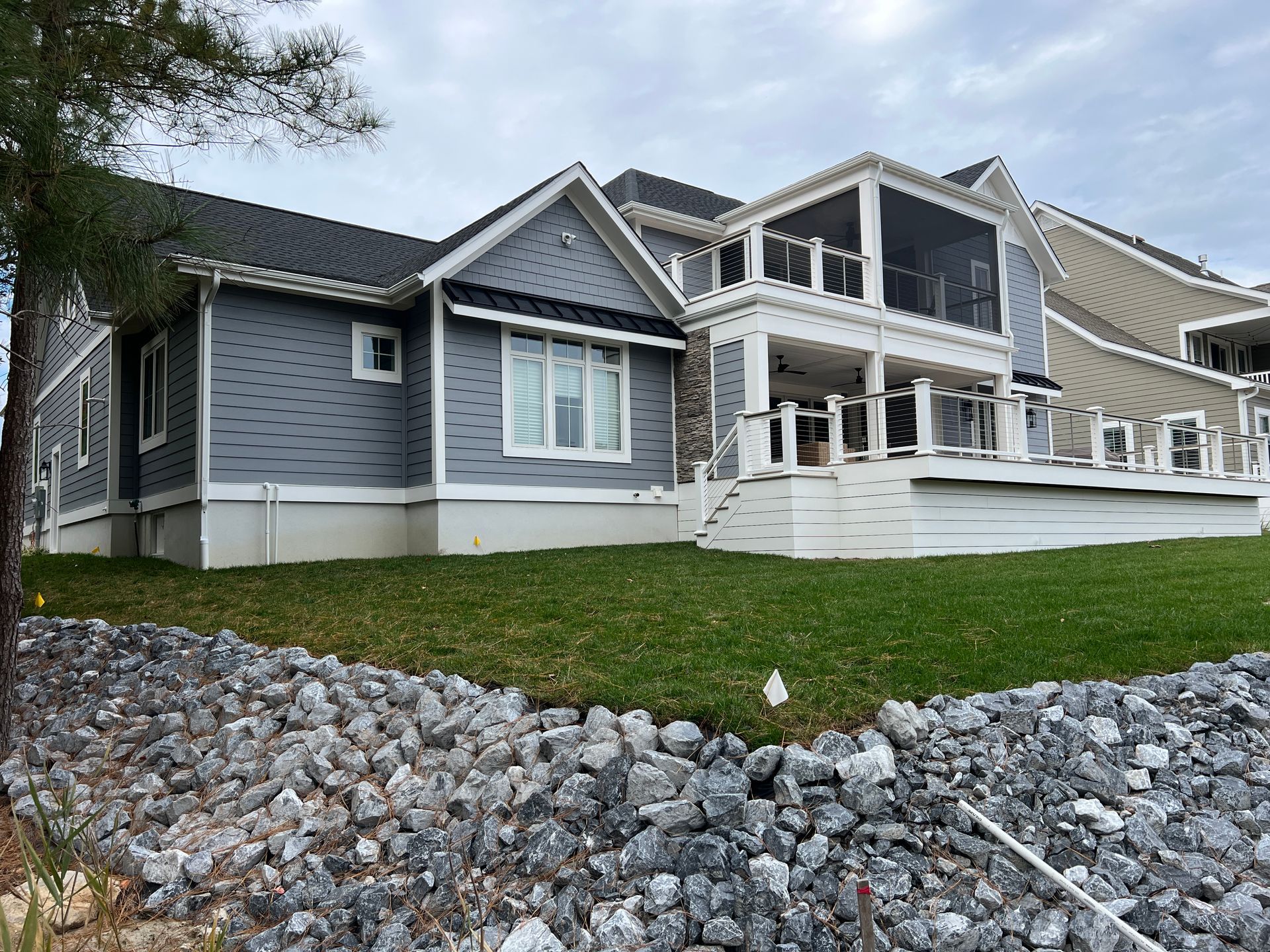 A large house with a screened-in porch is sitting on top of a lush green hillside.