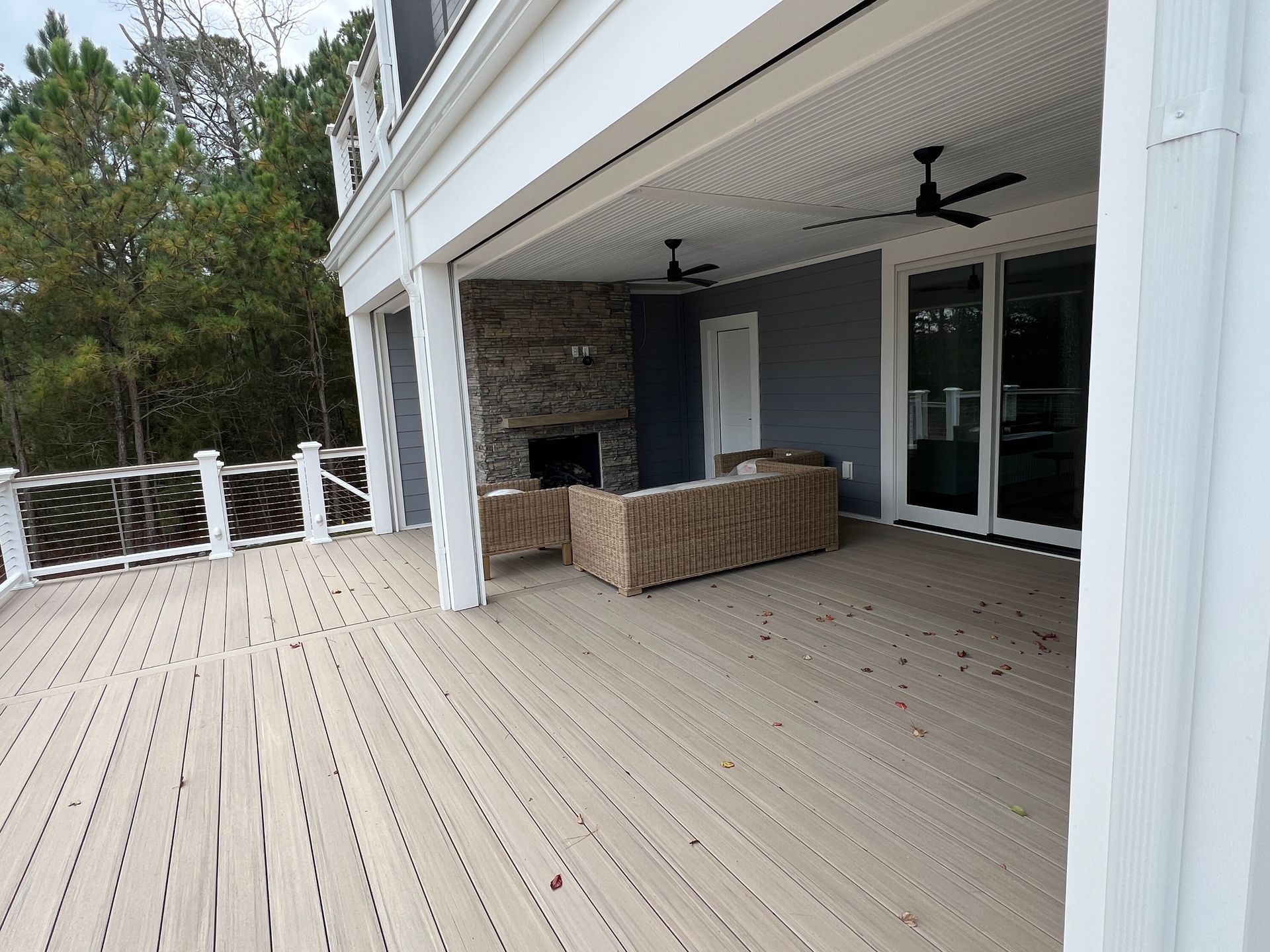 A large deck with a fireplace and ceiling fan.