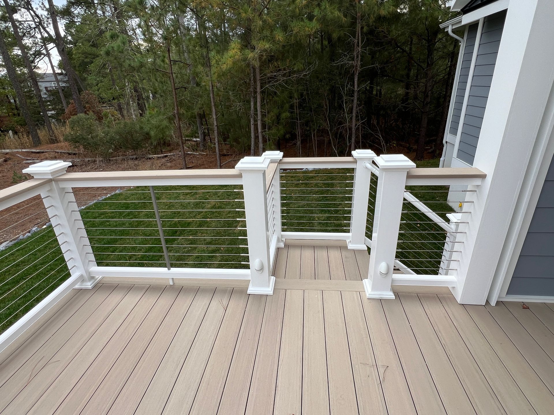 A wooden deck with a white railing and stairs leading to it.