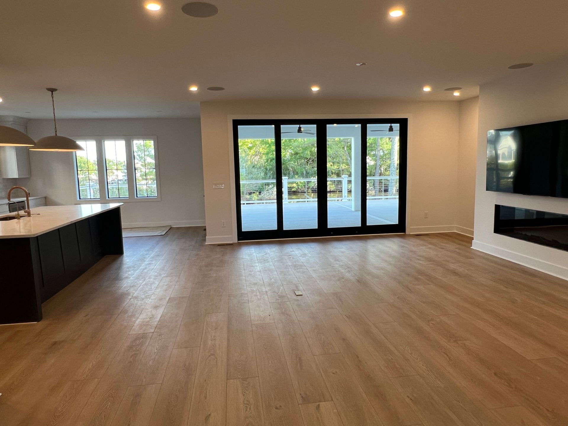A large empty room with hardwood floors and sliding glass doors.