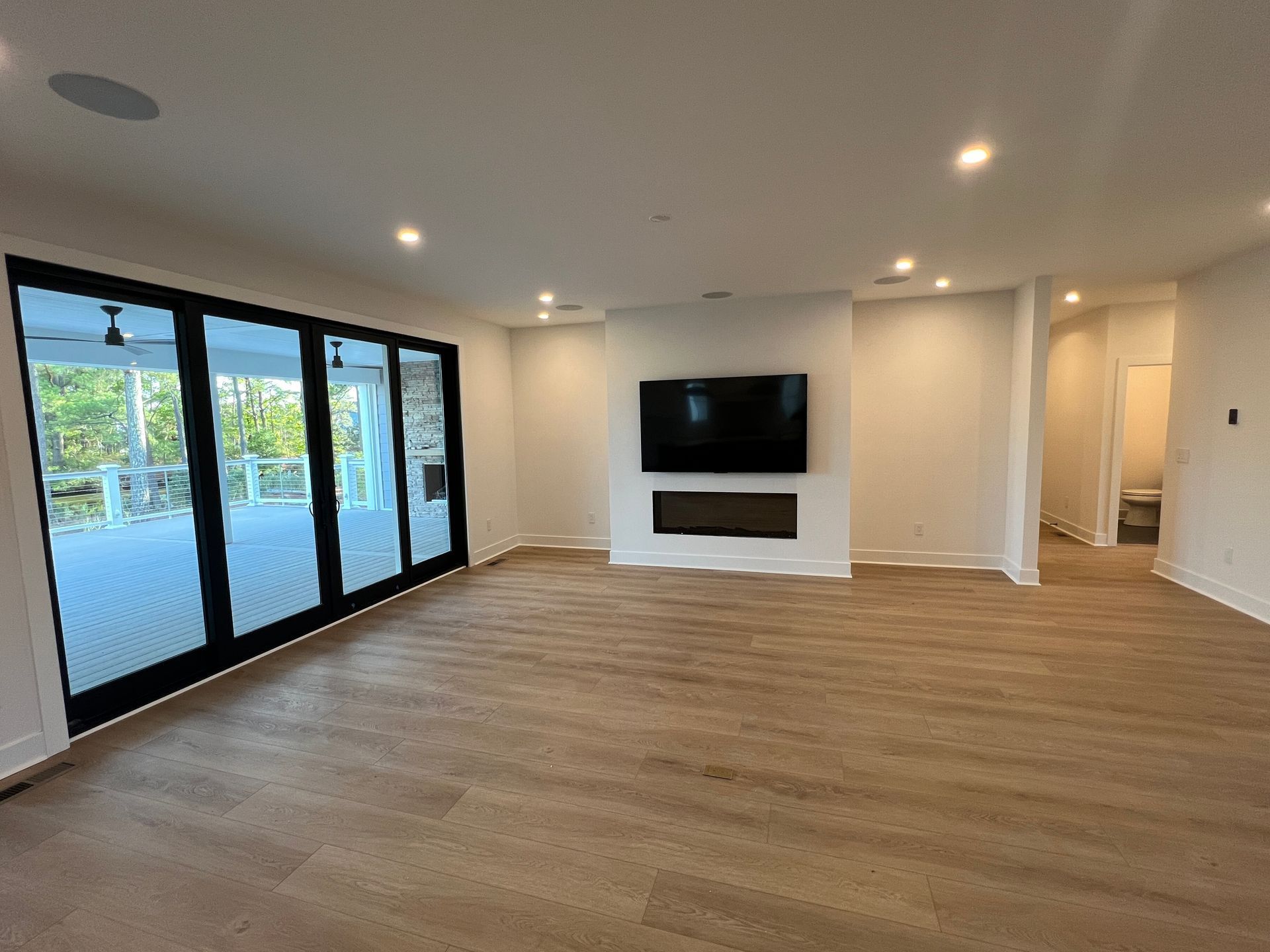 An empty living room with hardwood floors and a flat screen tv.
