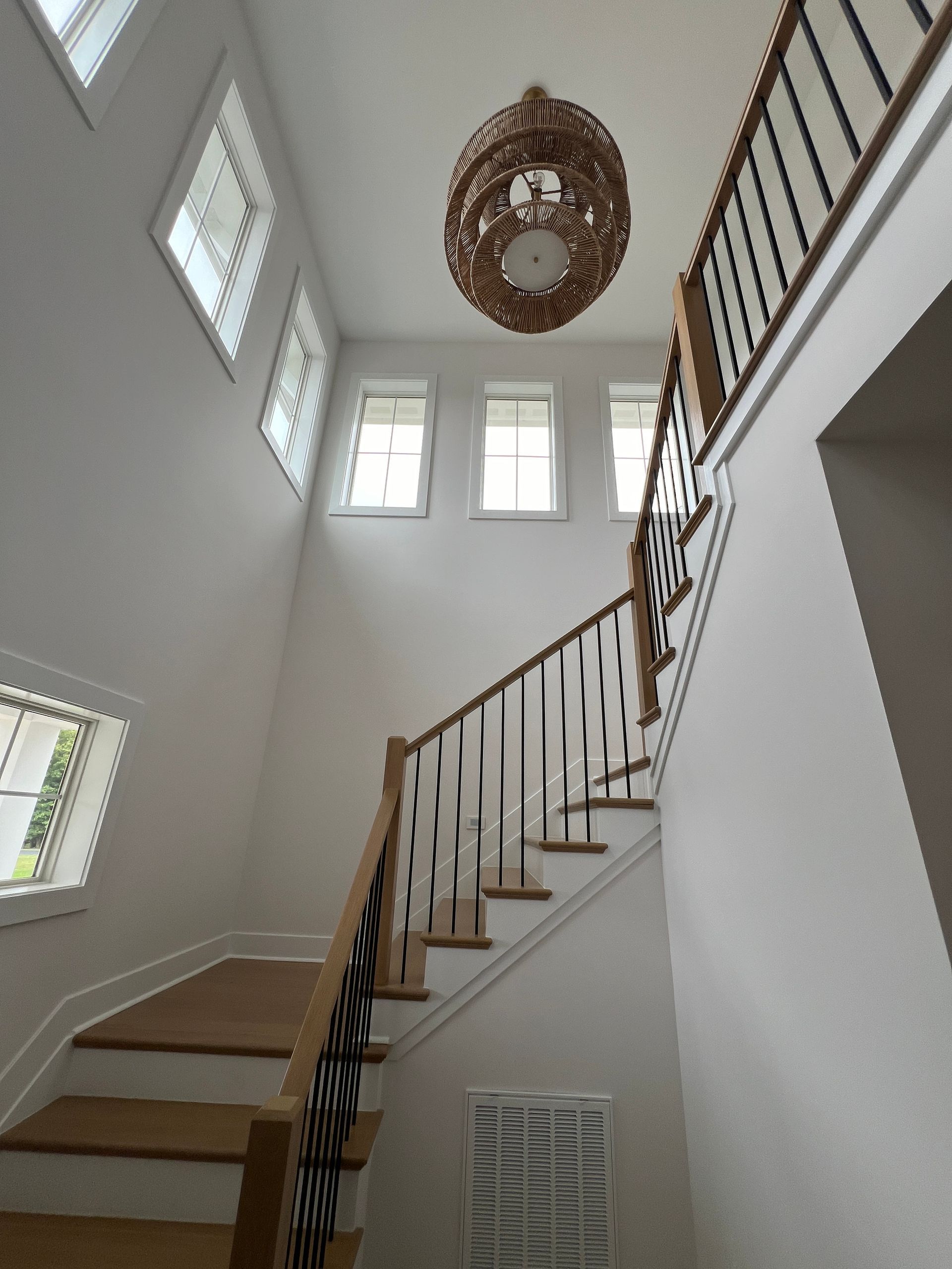 A staircase with a wooden railing and a chandelier hanging from the ceiling.