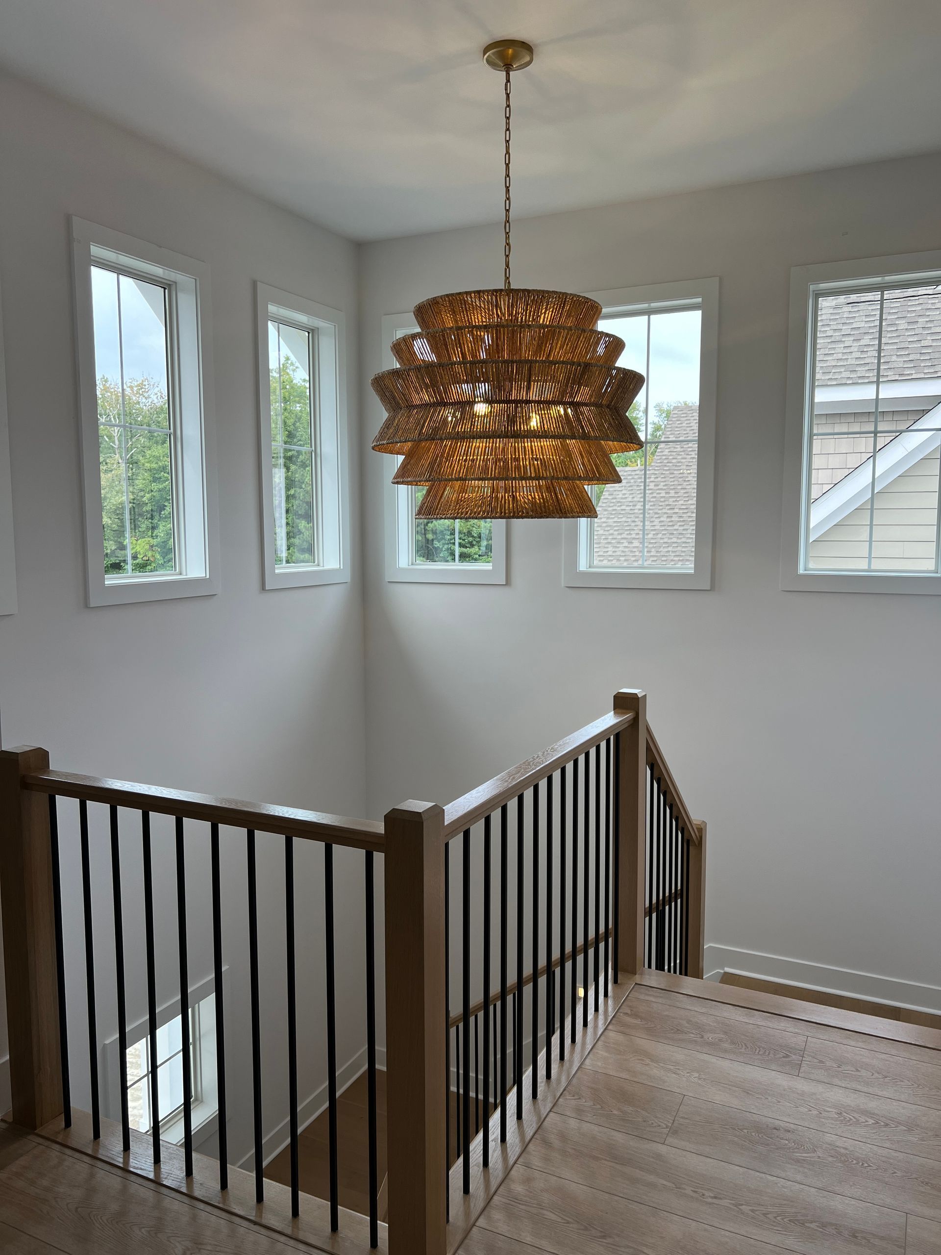 A staircase with a wooden railing and a chandelier hanging from the ceiling.