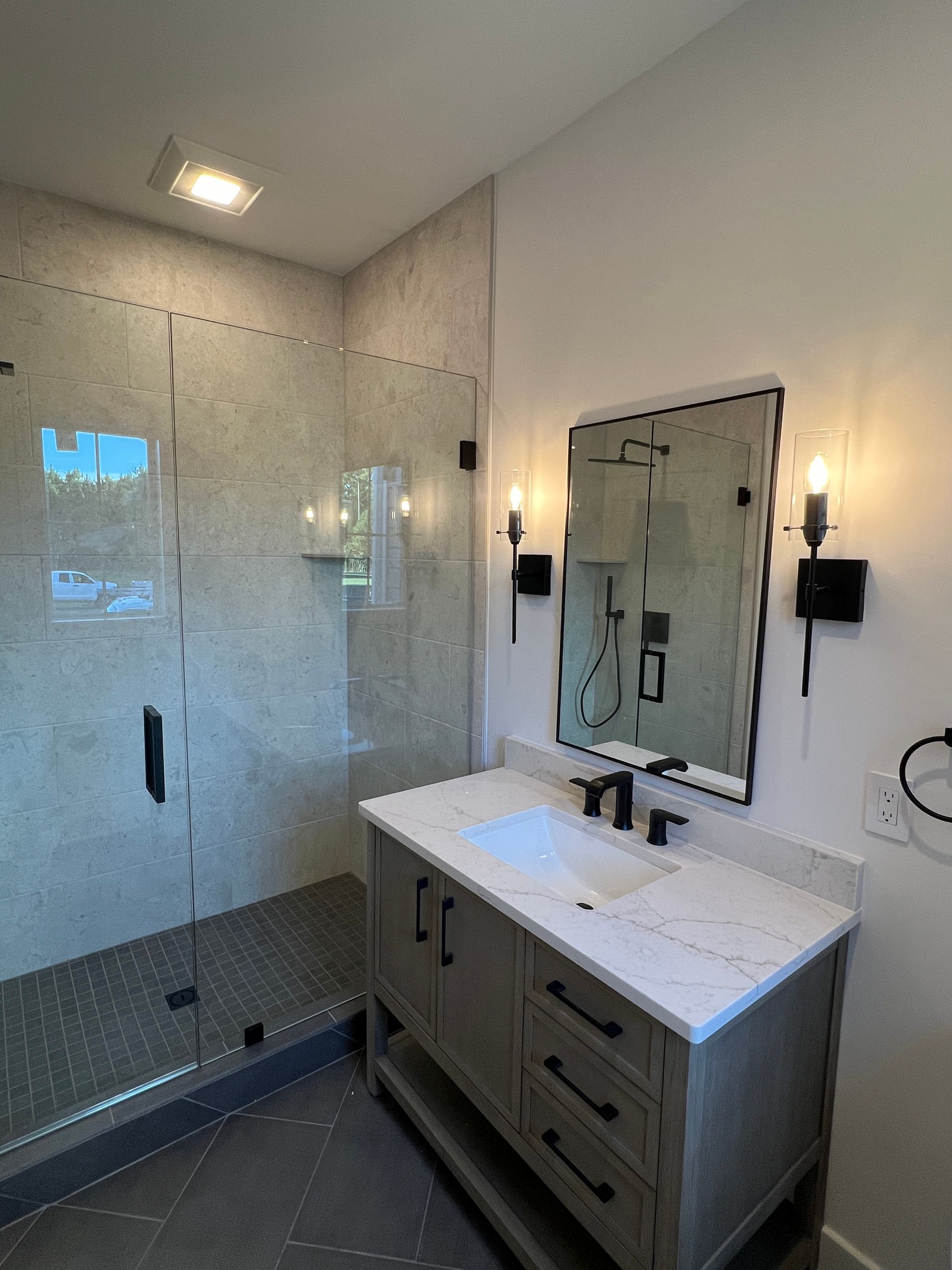 A bathroom with a sink , mirror and walk in shower.