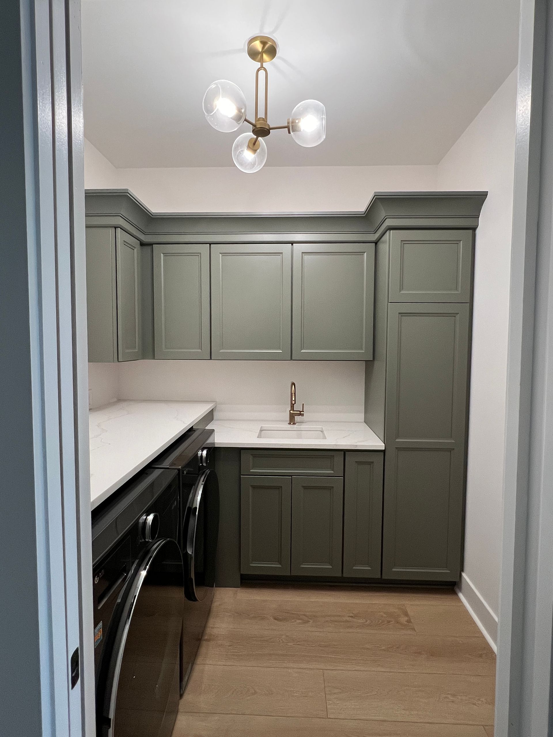 A laundry room with green cabinets and a washer and dryer.