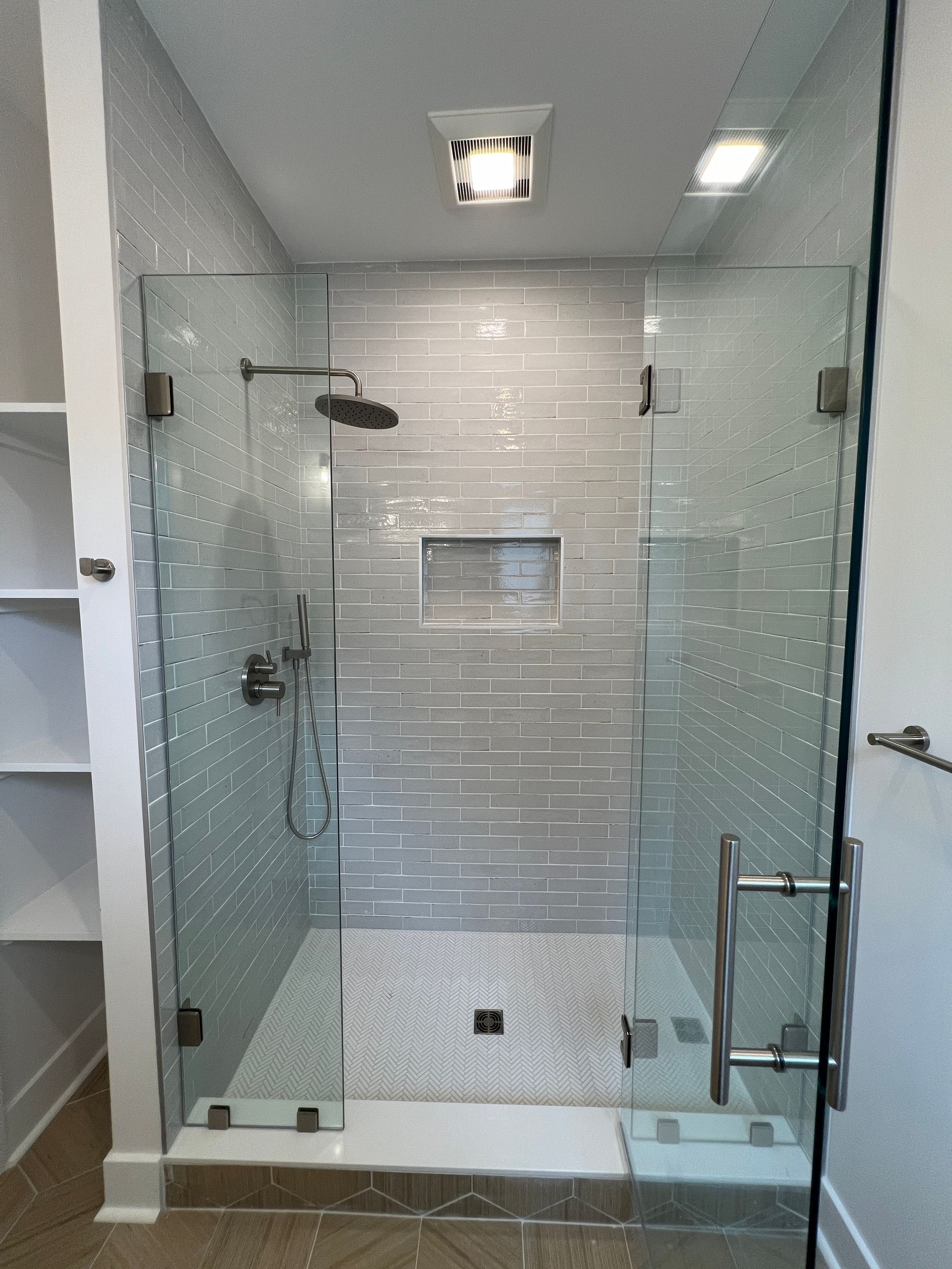 A bathroom with a walk in shower with a glass door.