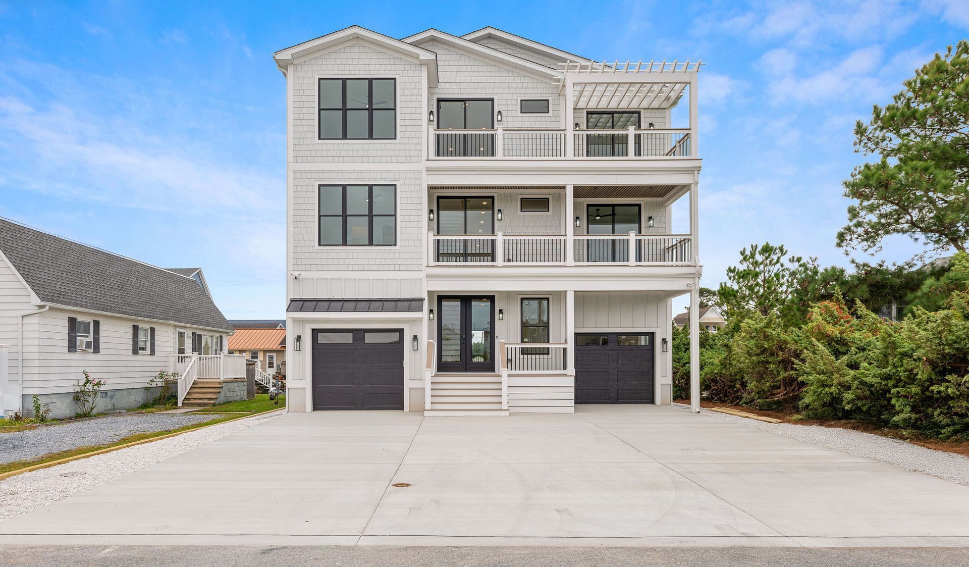 A large white house with black garage doors is for sale.