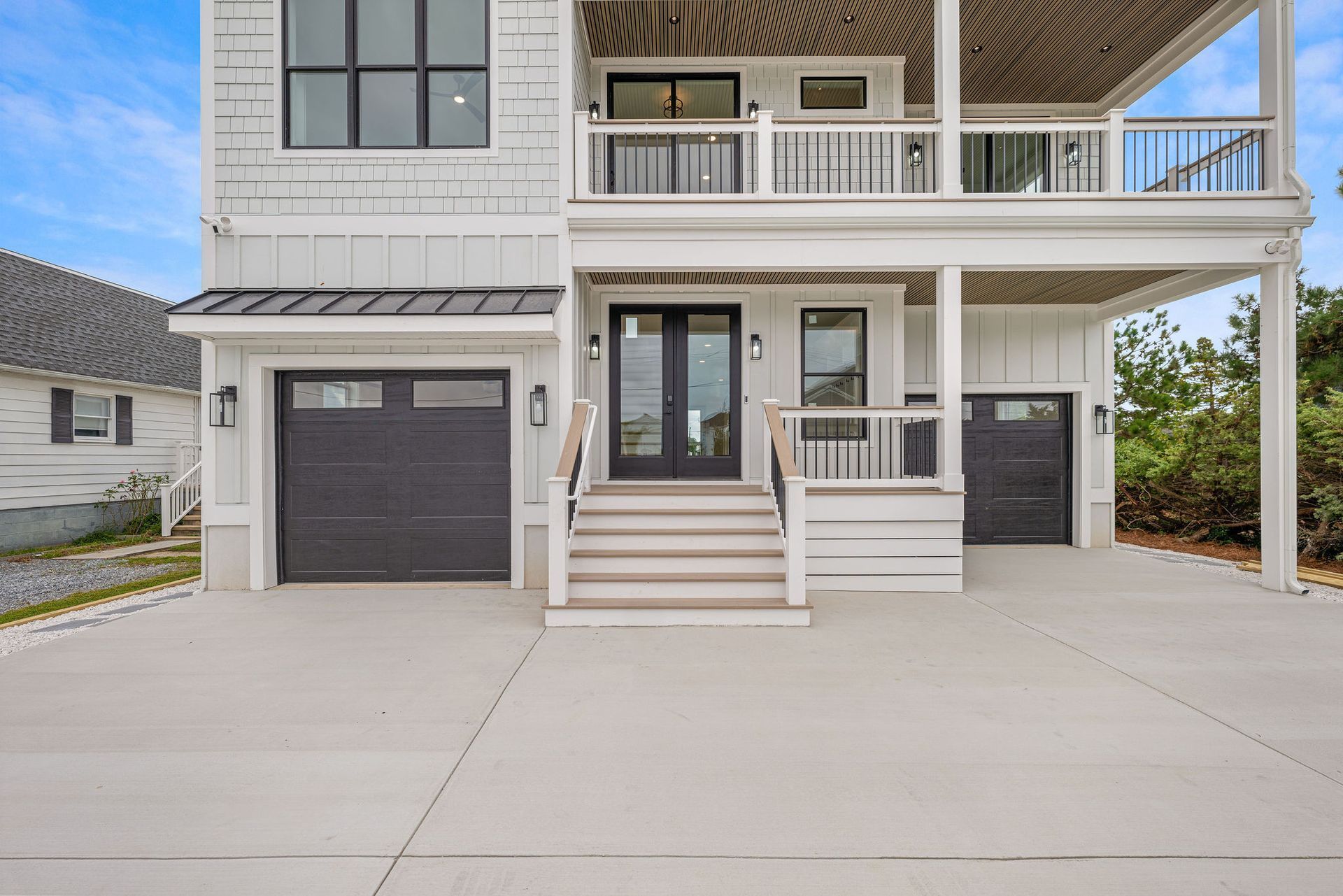 A large white house with a black garage door and stairs.