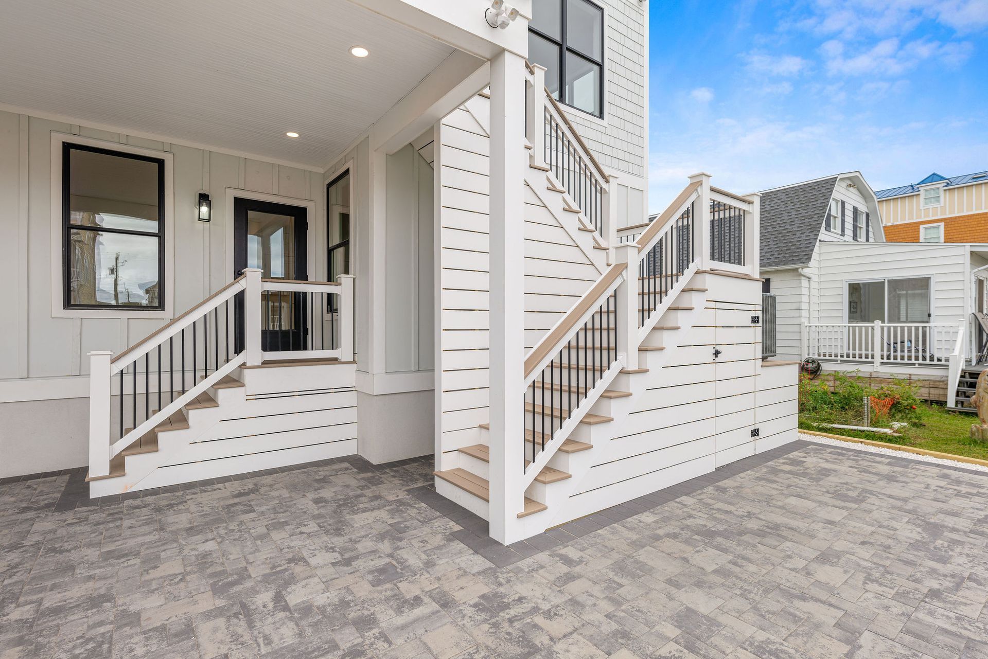 A white house with stairs leading up to the second floor.