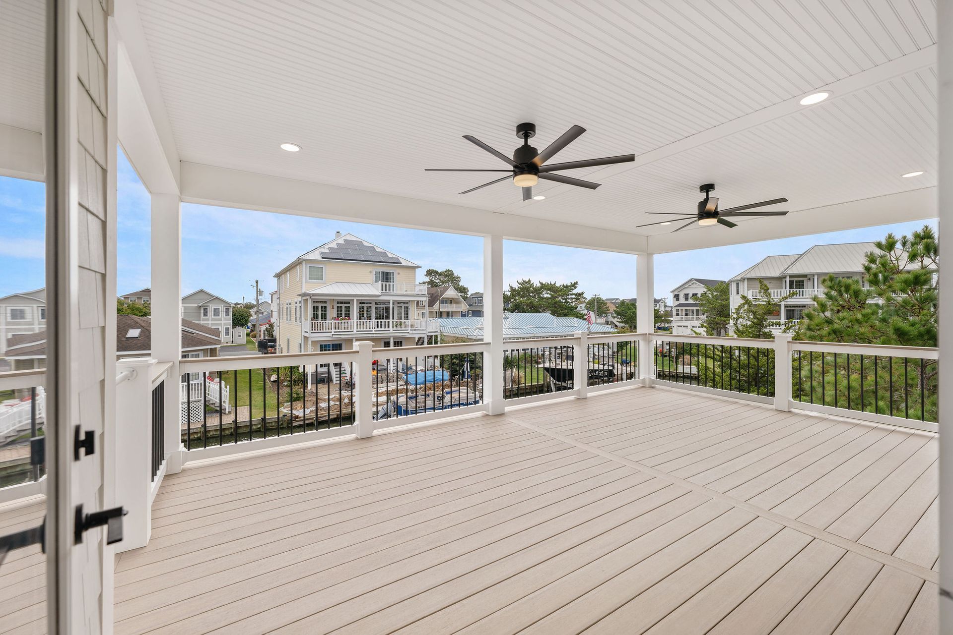 There are two ceiling fans on the deck of a house.