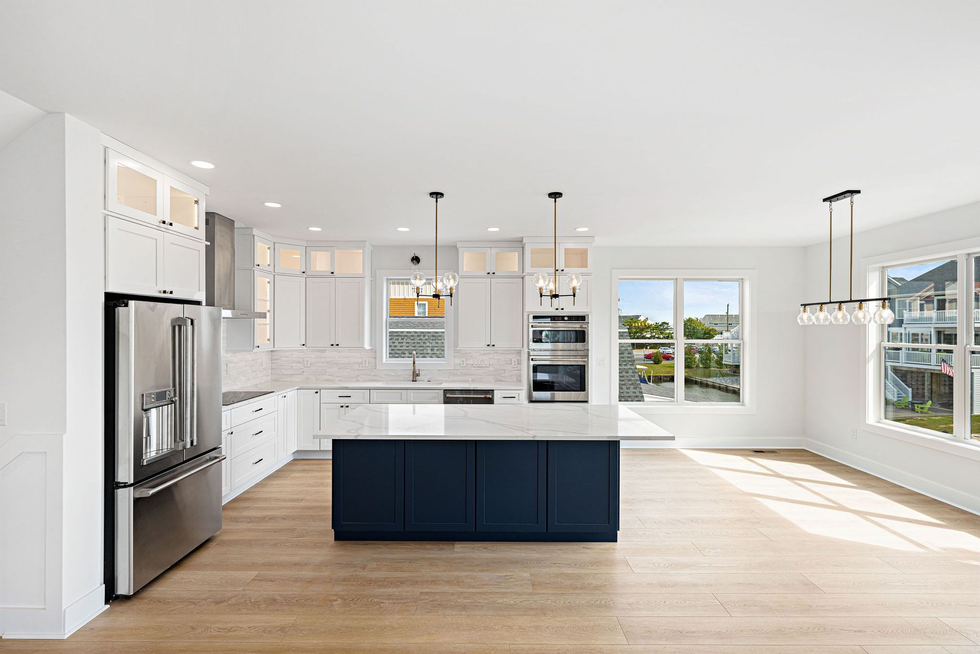 A kitchen with white cabinets, stainless steel appliances, and a blue island.