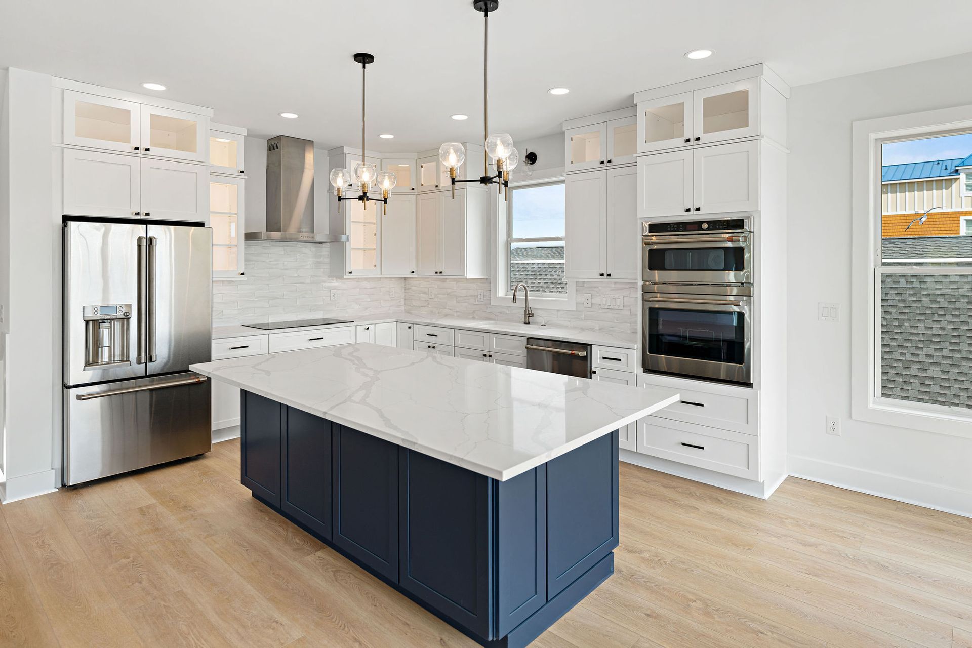 A kitchen with white cabinets , stainless steel appliances , and a large island.