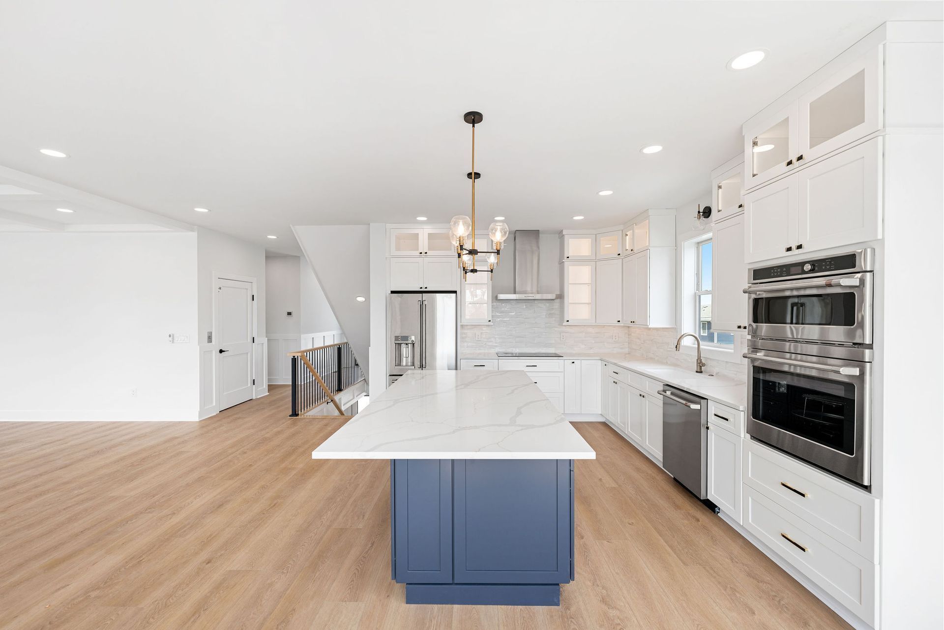 A kitchen with white cabinets and stainless steel appliances and a blue island.