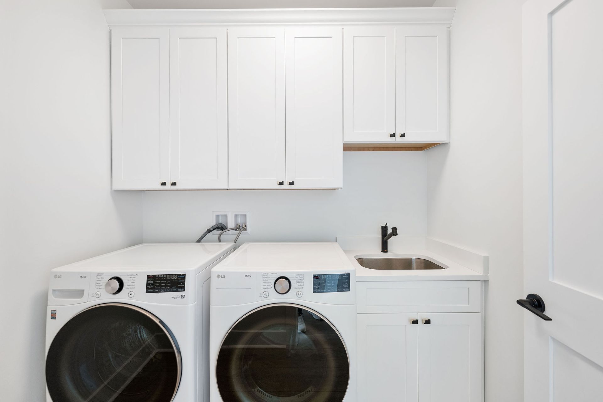 A laundry room with a washer and dryer and a sink.