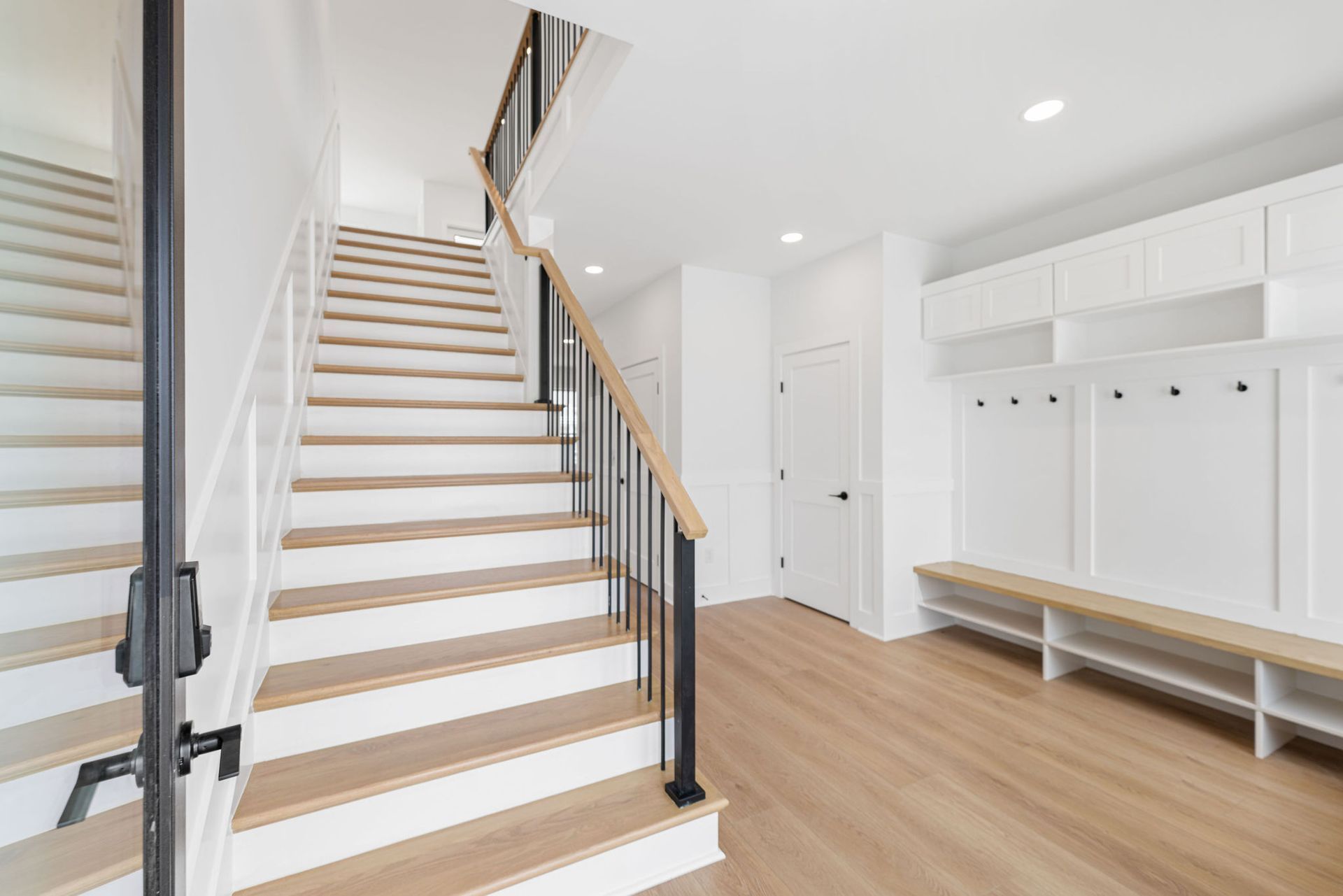 A hallway with stairs and a bench in a house.