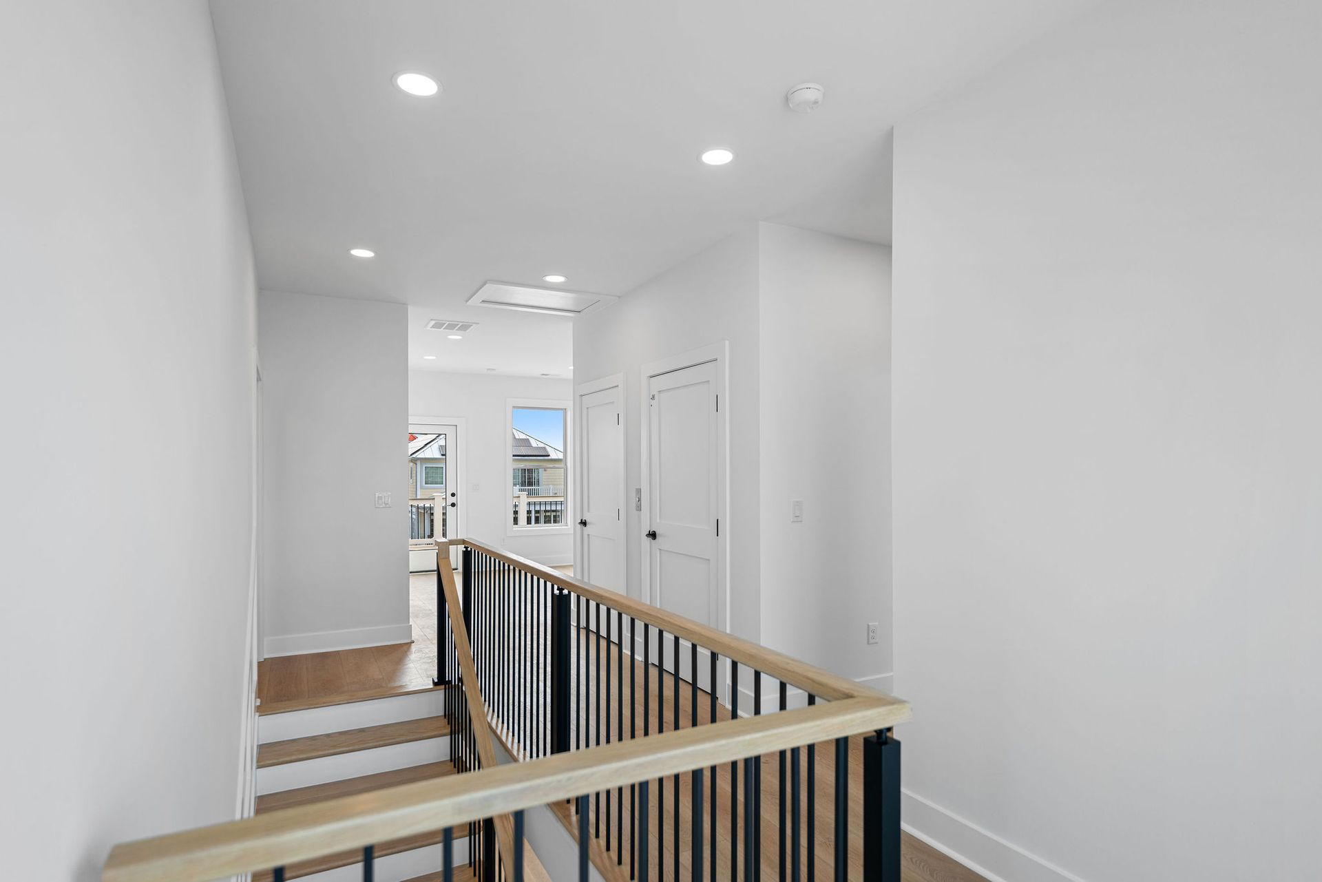 A hallway with stairs and a railing in a house.