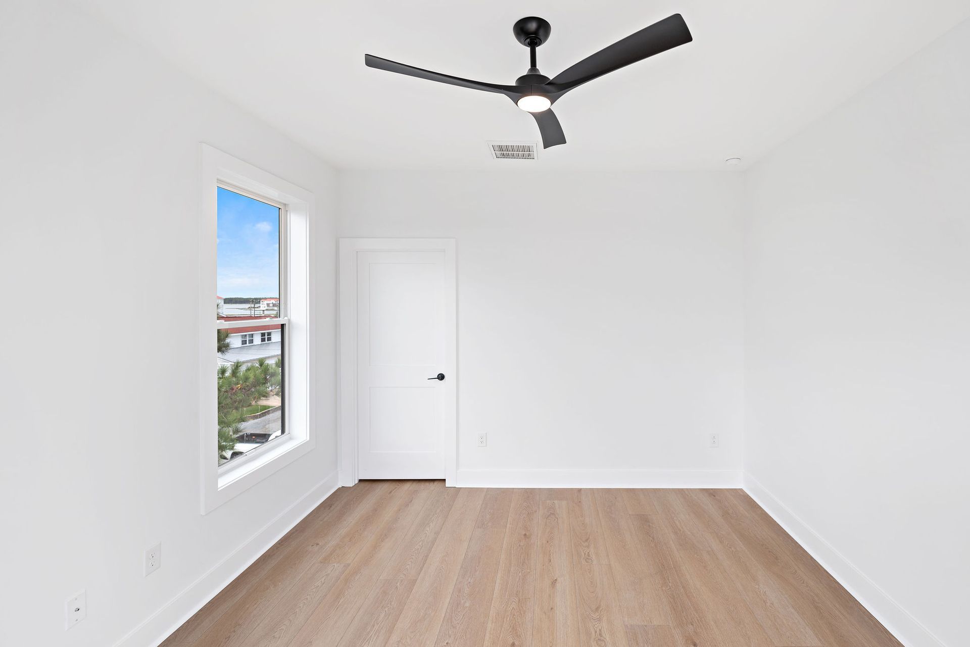 An empty room with a ceiling fan and a window.