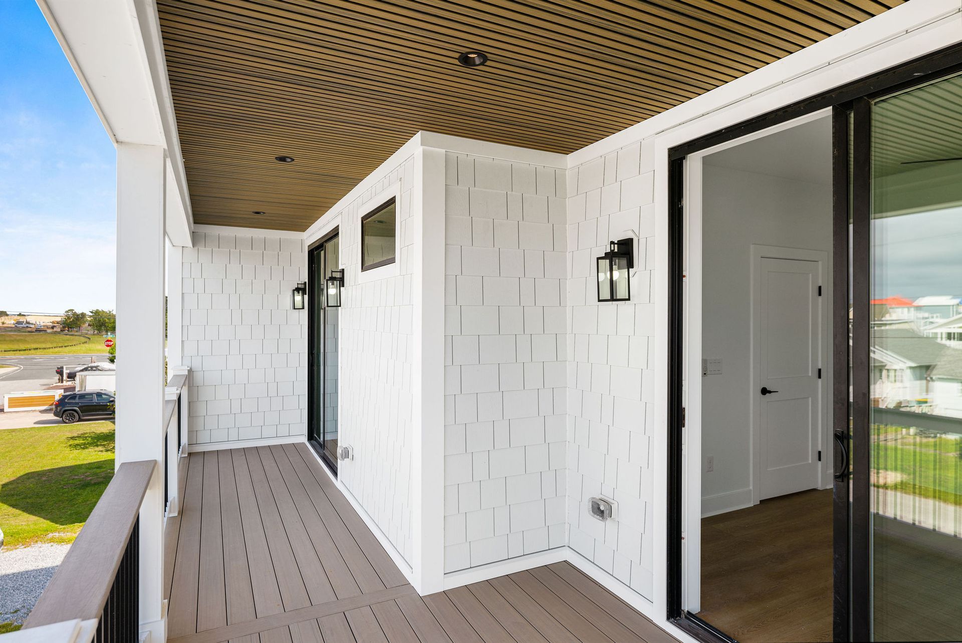 A balcony with sliding glass doors and a wooden floor in a house.