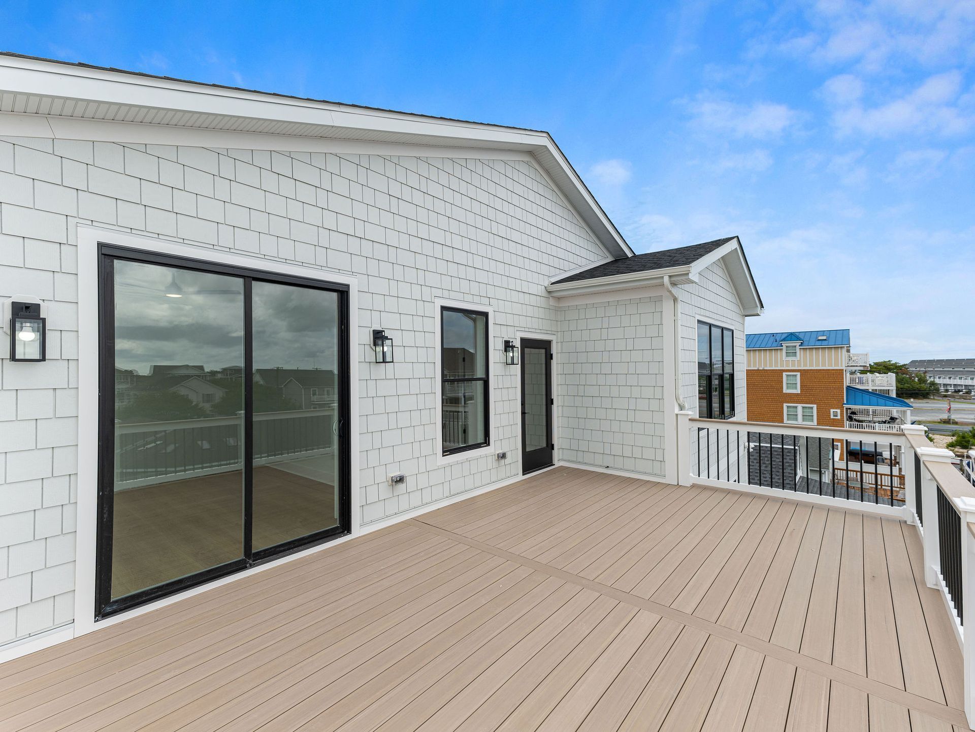 A large deck with sliding glass doors on the side of a house.
