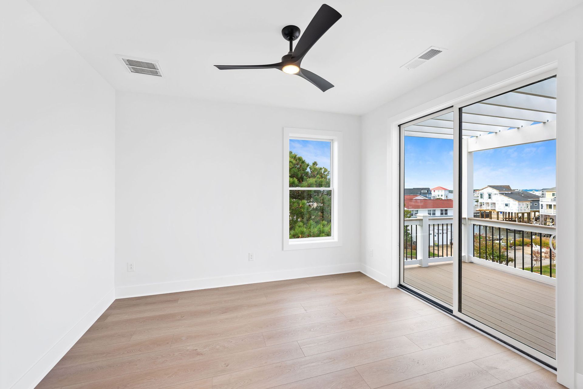 An empty room with a ceiling fan and sliding glass doors.