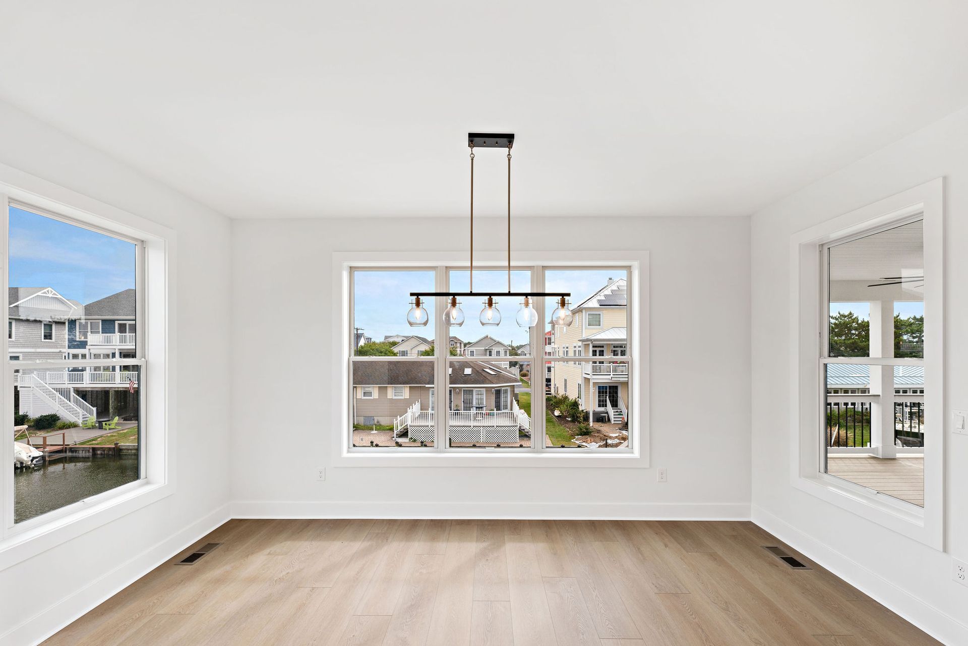 An empty dining room with hardwood floors and a chandelier.