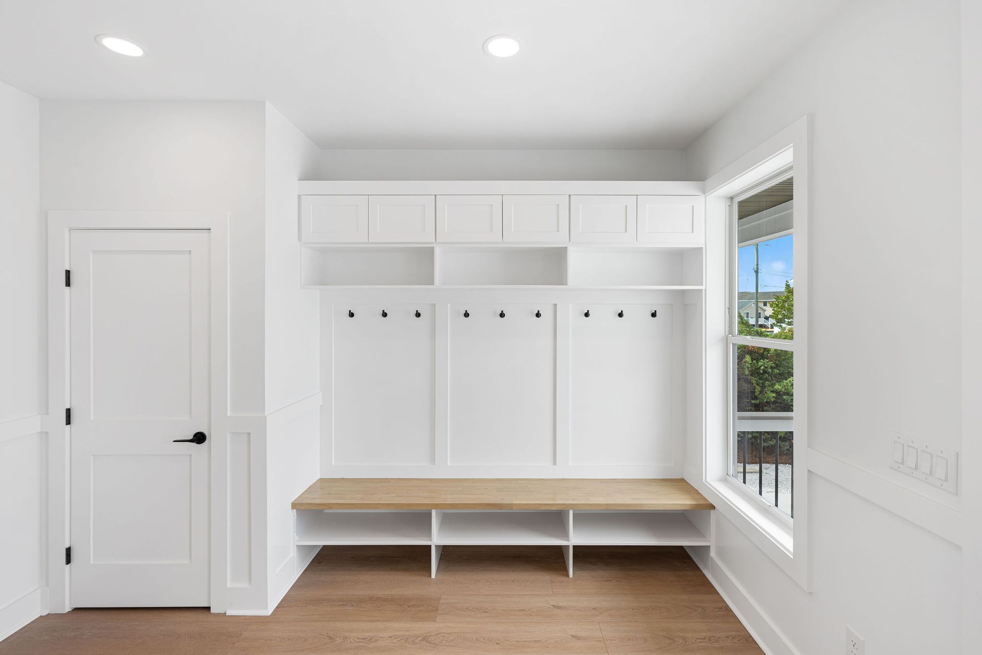 A white room with a wooden bench and a window.