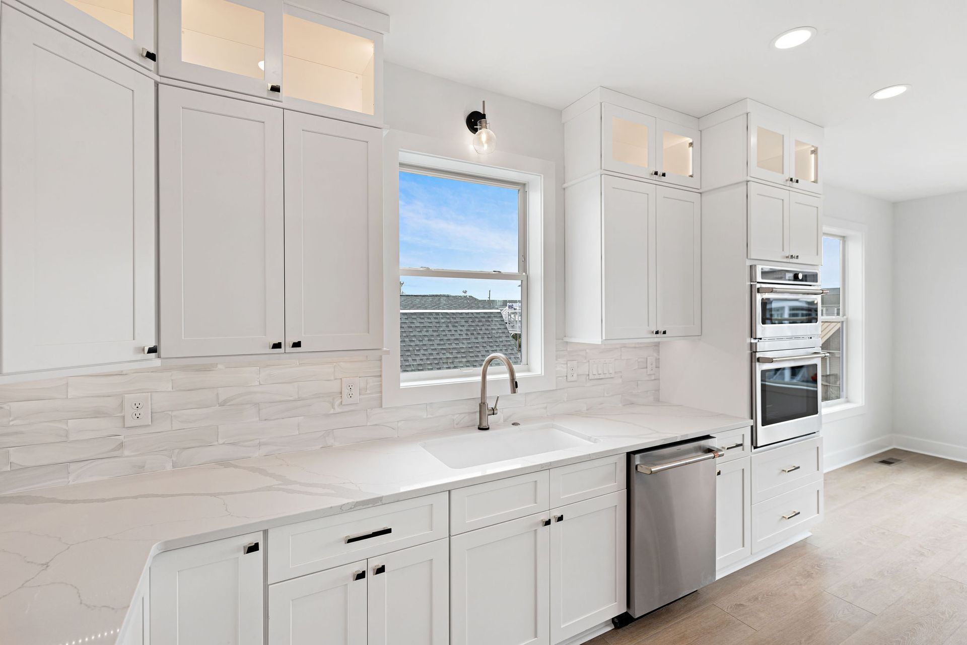 A kitchen with white cabinets, stainless steel appliances, a sink, and a window.