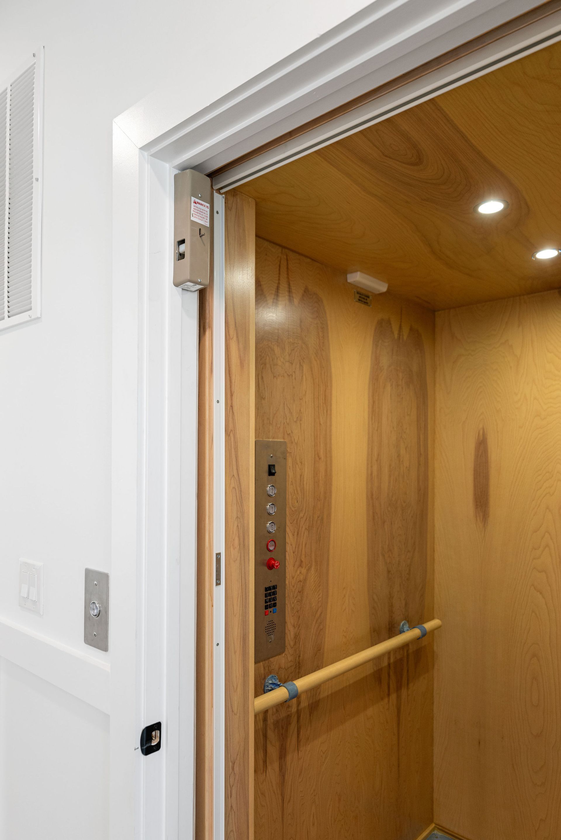 A wooden elevator with a door open and buttons on the wall.