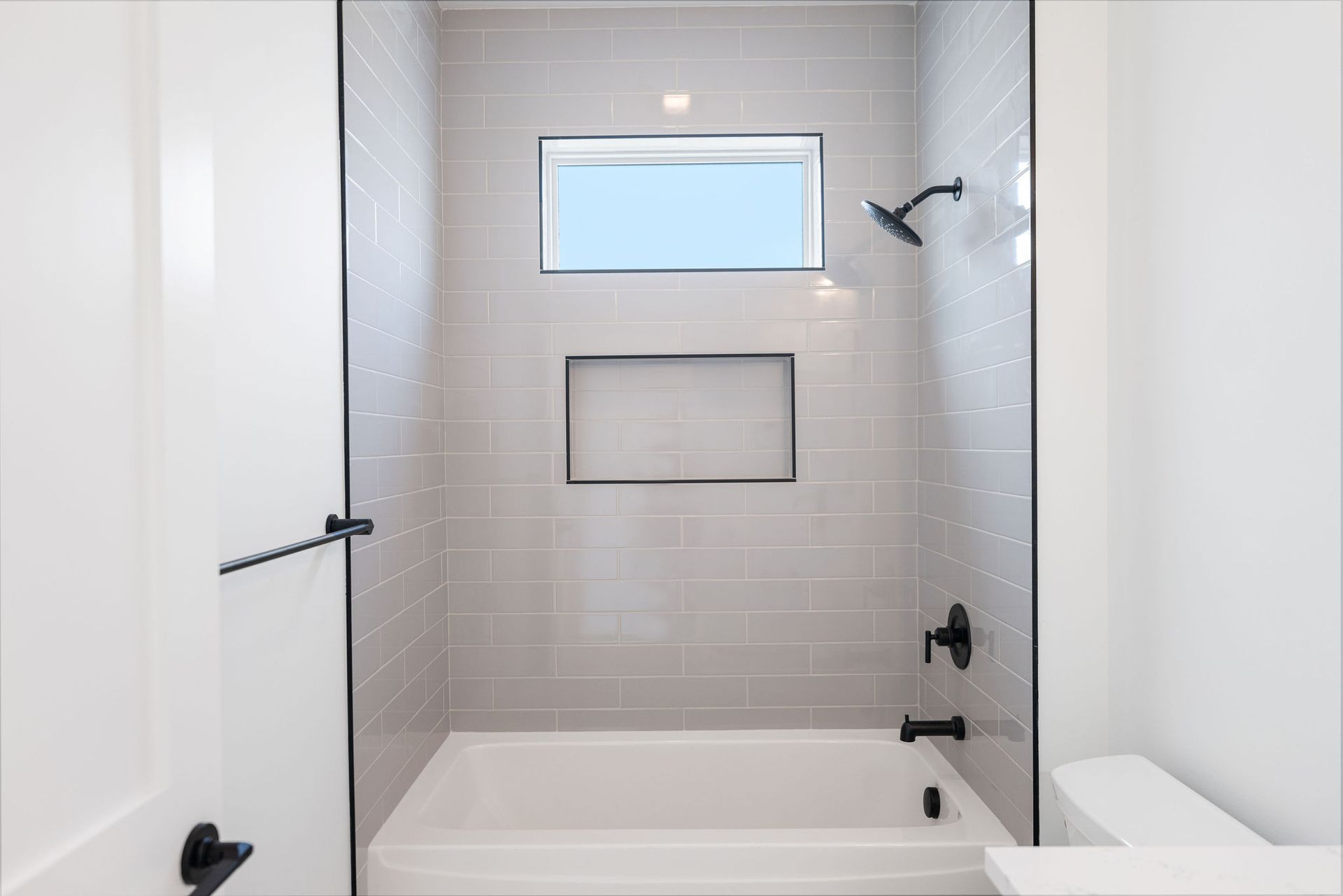 A bathroom with a tub and a shower with a window.