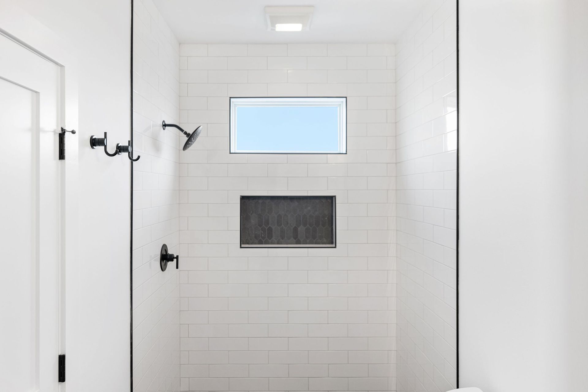 A bathroom with a walk in shower and a window.