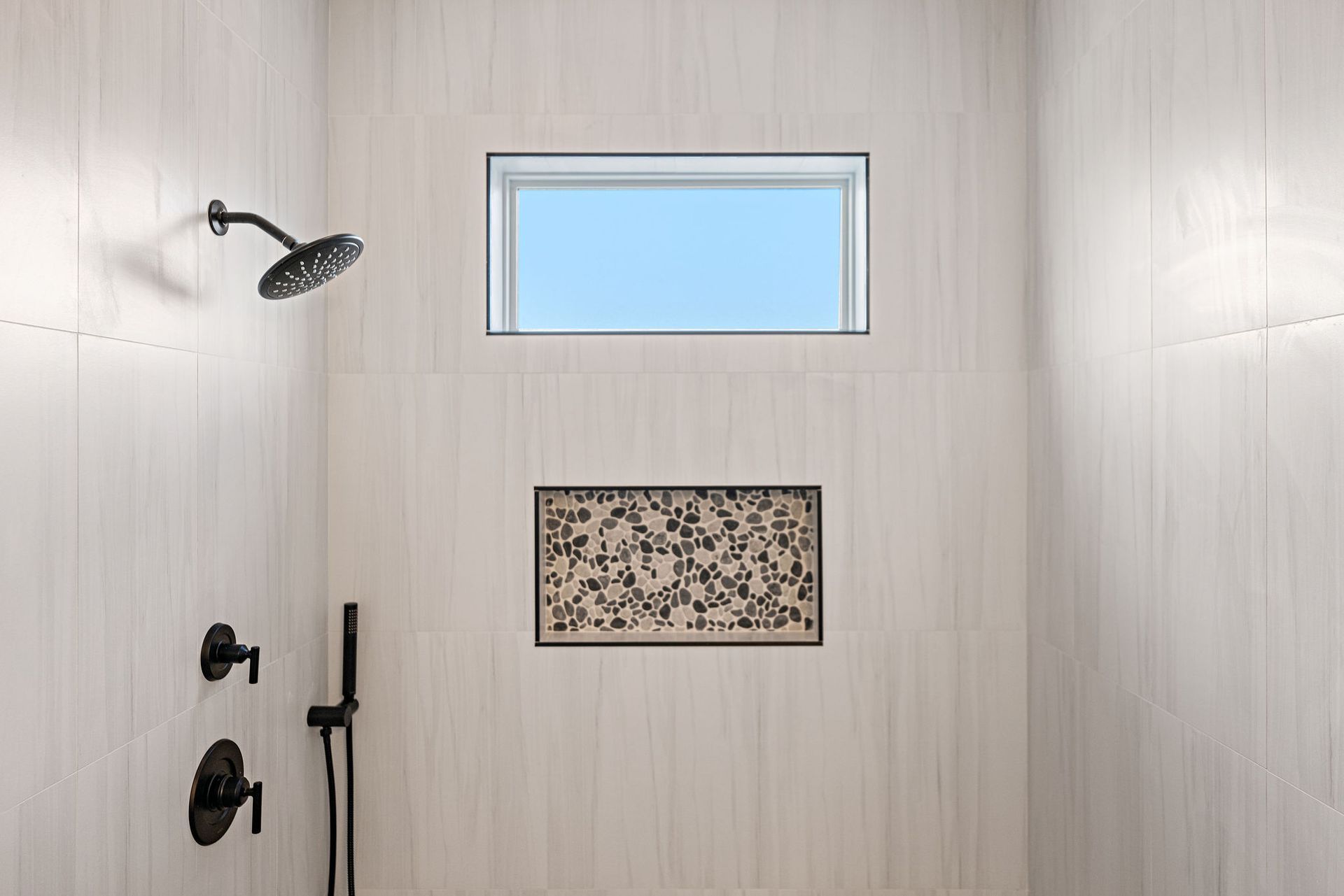 A shower with a window and a shower head.