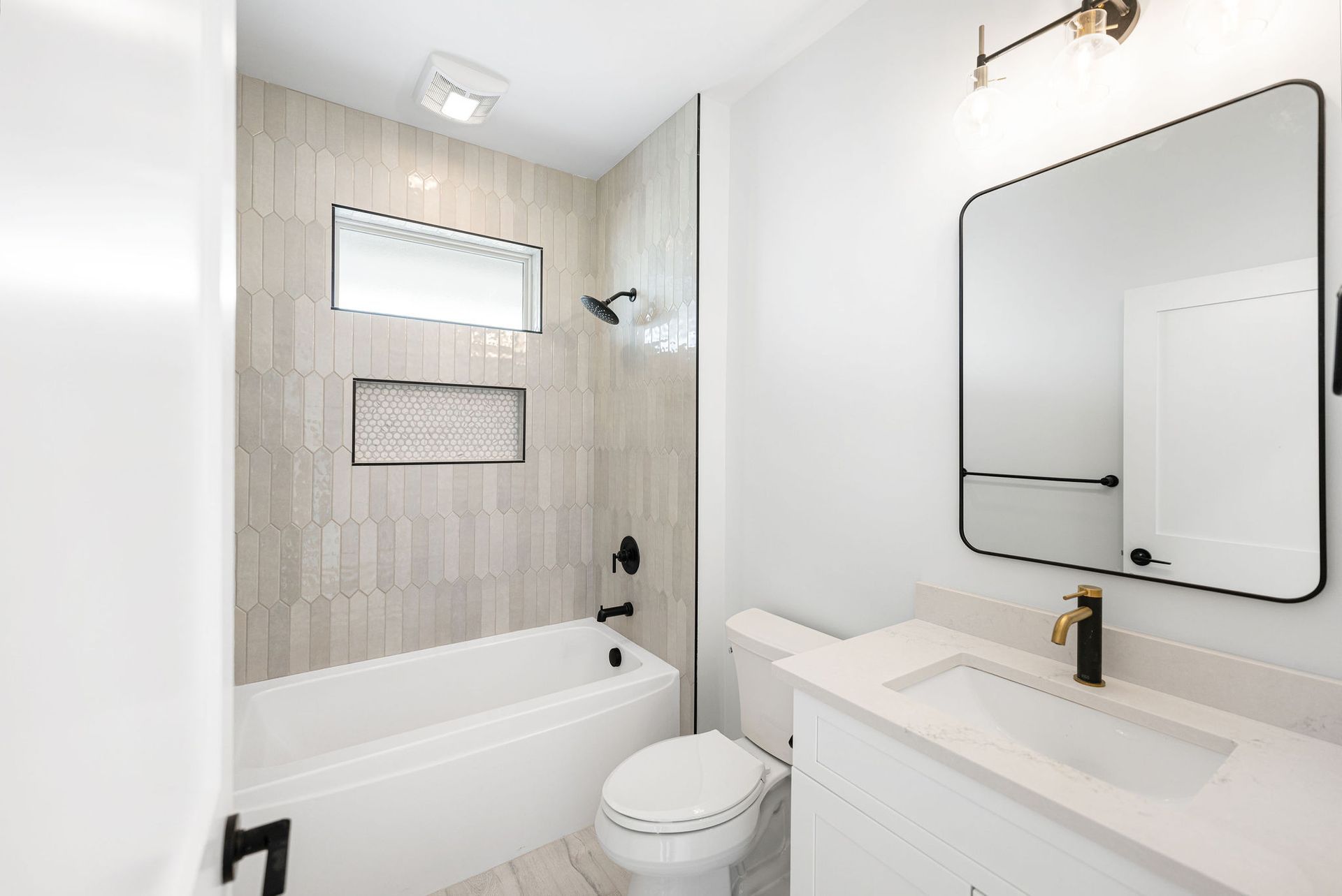 A bathroom with a toilet, sink, bathtub and mirror.
