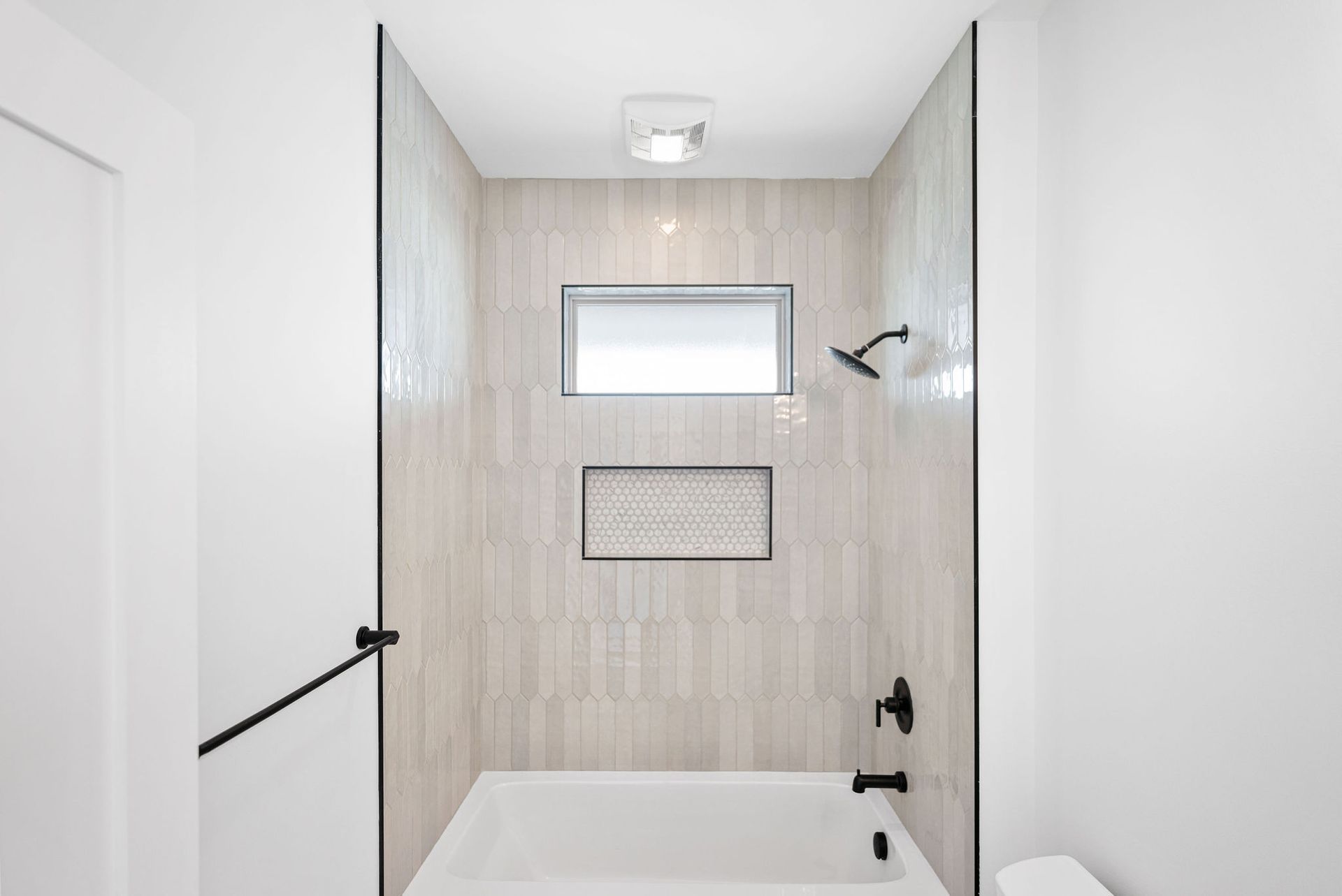 A bathroom with a tub, shower and window.