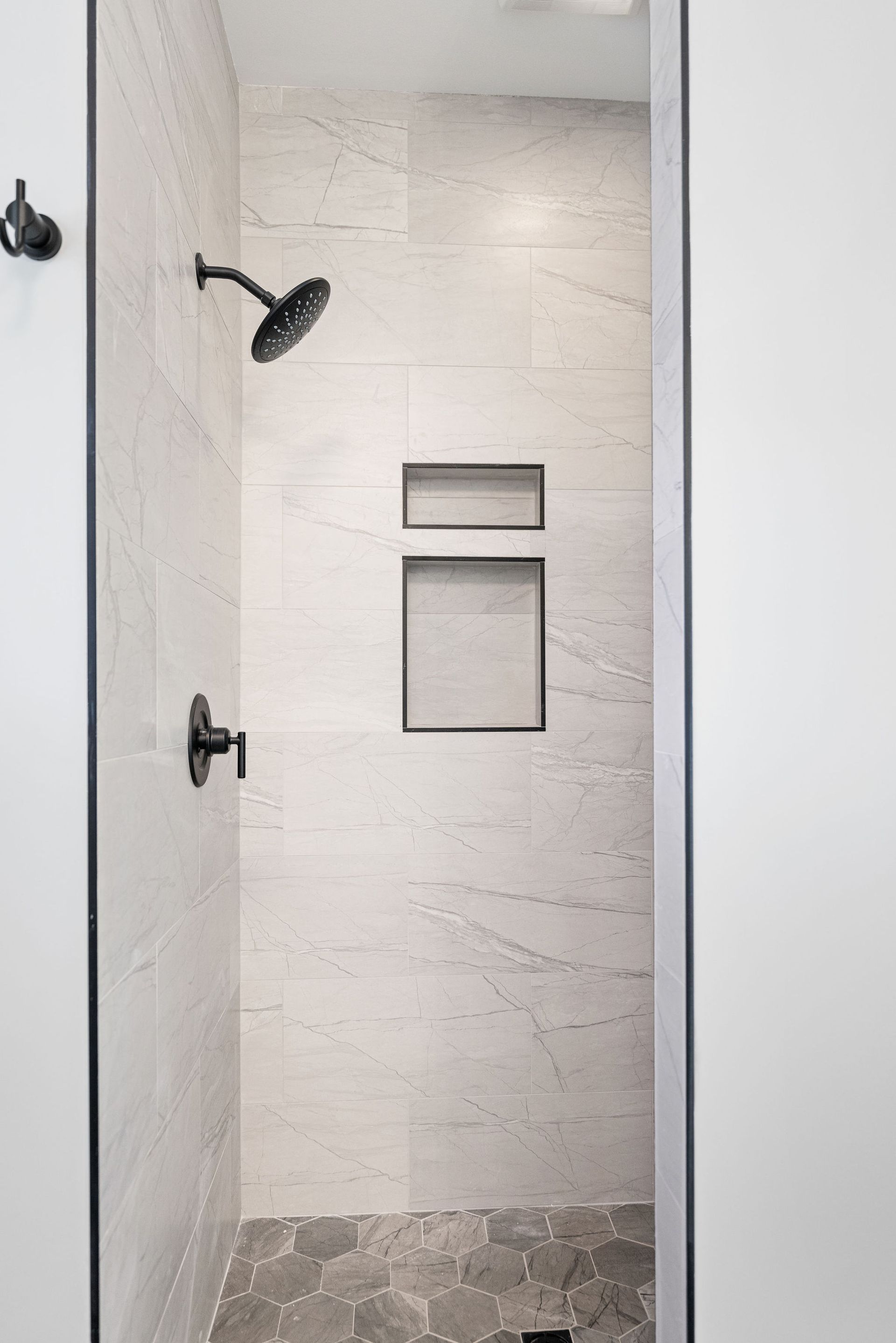 A shower with a shower head and a shelf in the wall.