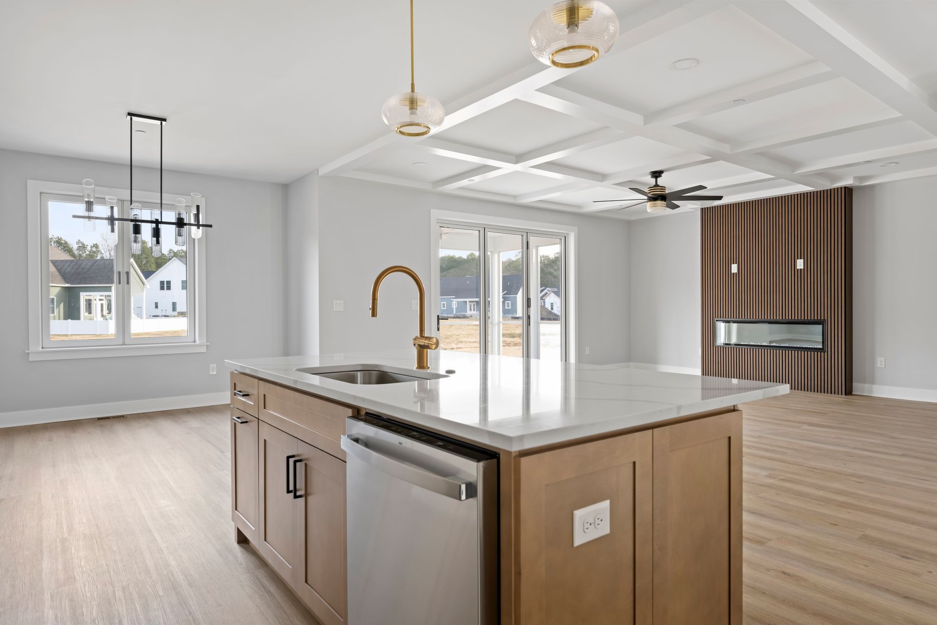Bright modern kitchen with island, pendant lights, and large windows opening to a living area