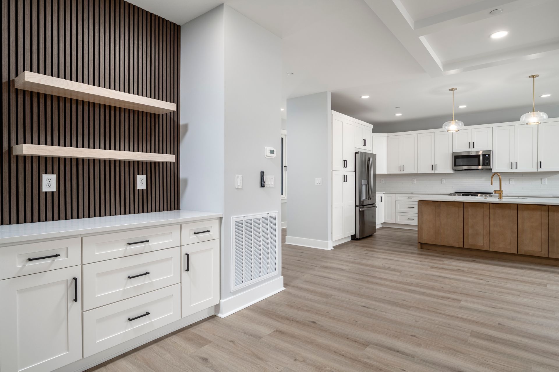 Modern open-concept kitchen with white cabinets, wood island, and striped accent wall