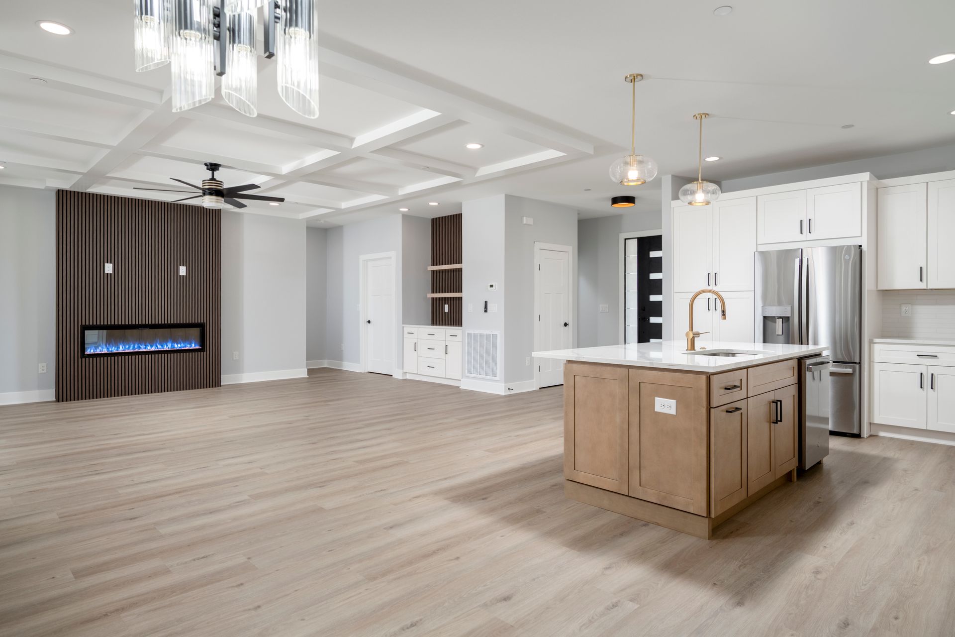 Spacious modern kitchen with white cabinets, wood island, and light wood flooring