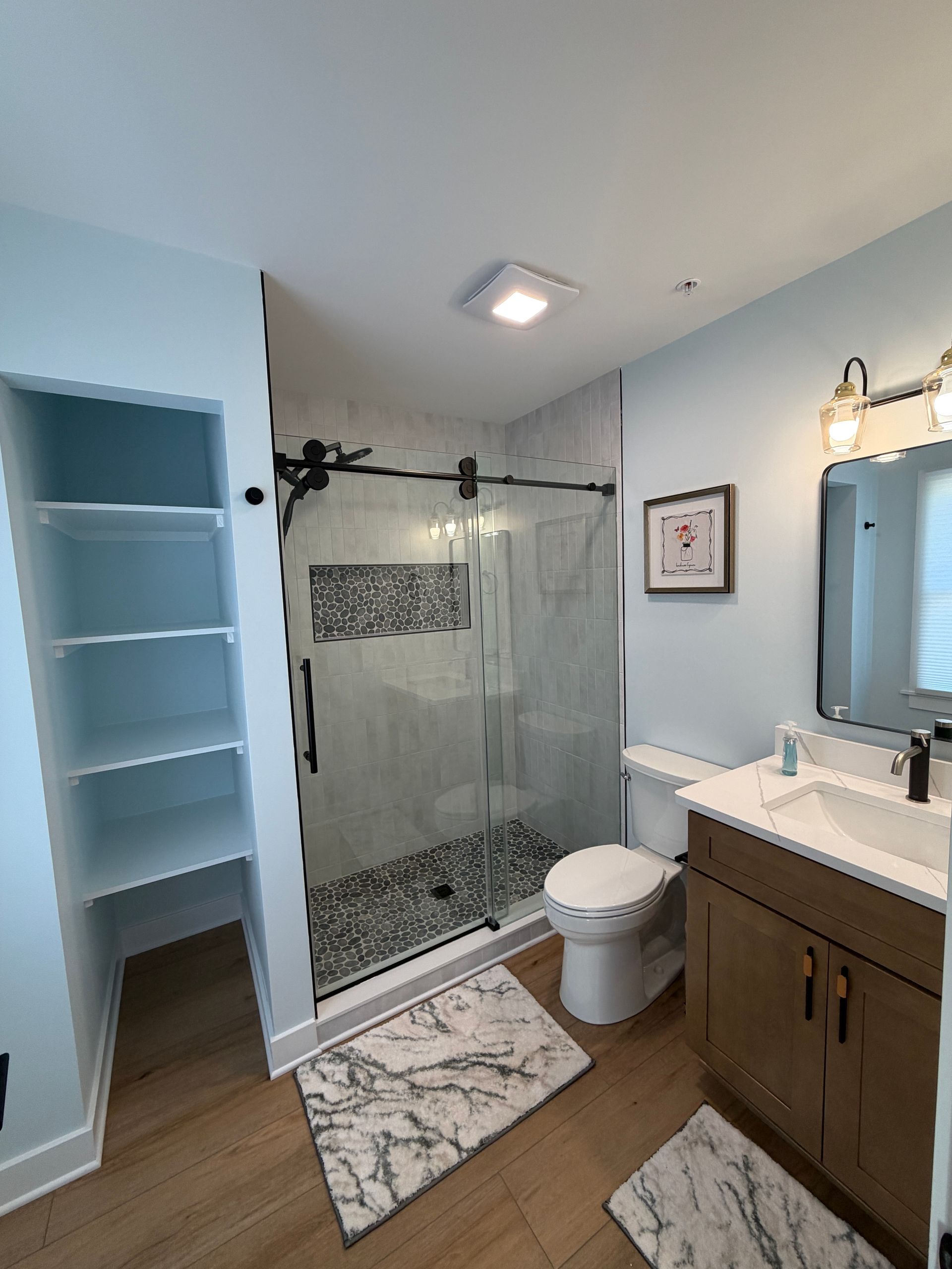 Modern bathroom with walk-in shower, toilet, vanity sink, and open shelving