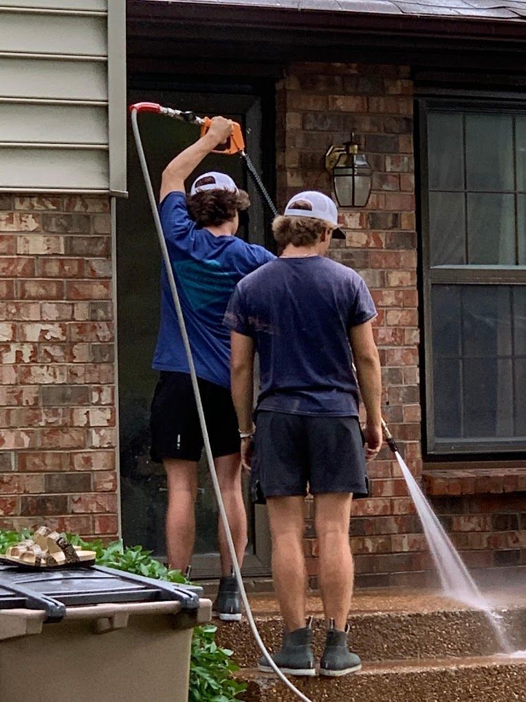 two boys pressure washing stairs